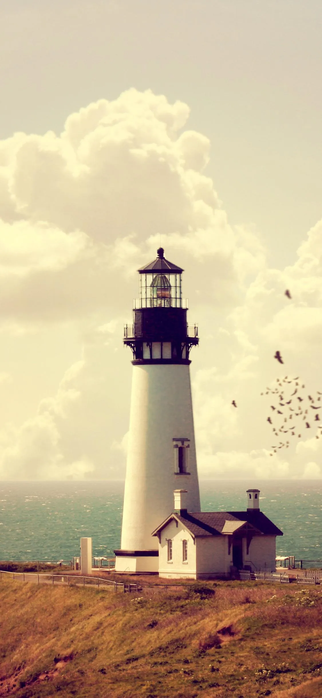 Lighthouse by the Sea under Cloudy Sky Scene Wallpaper