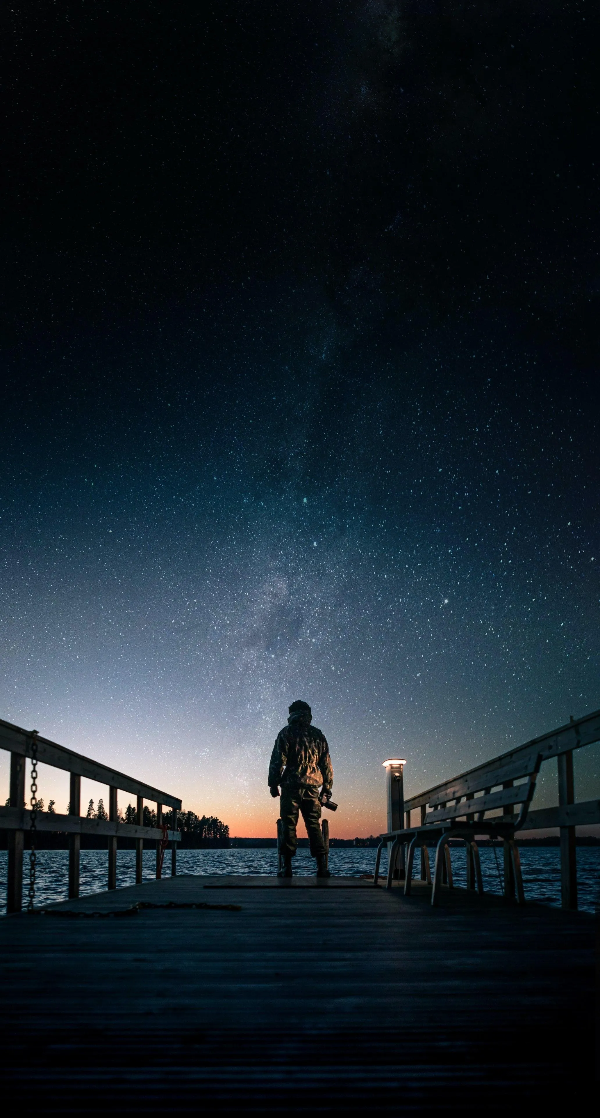 Lone Figure Walking on Bridge Toward Star Lit Sky Wallpaper