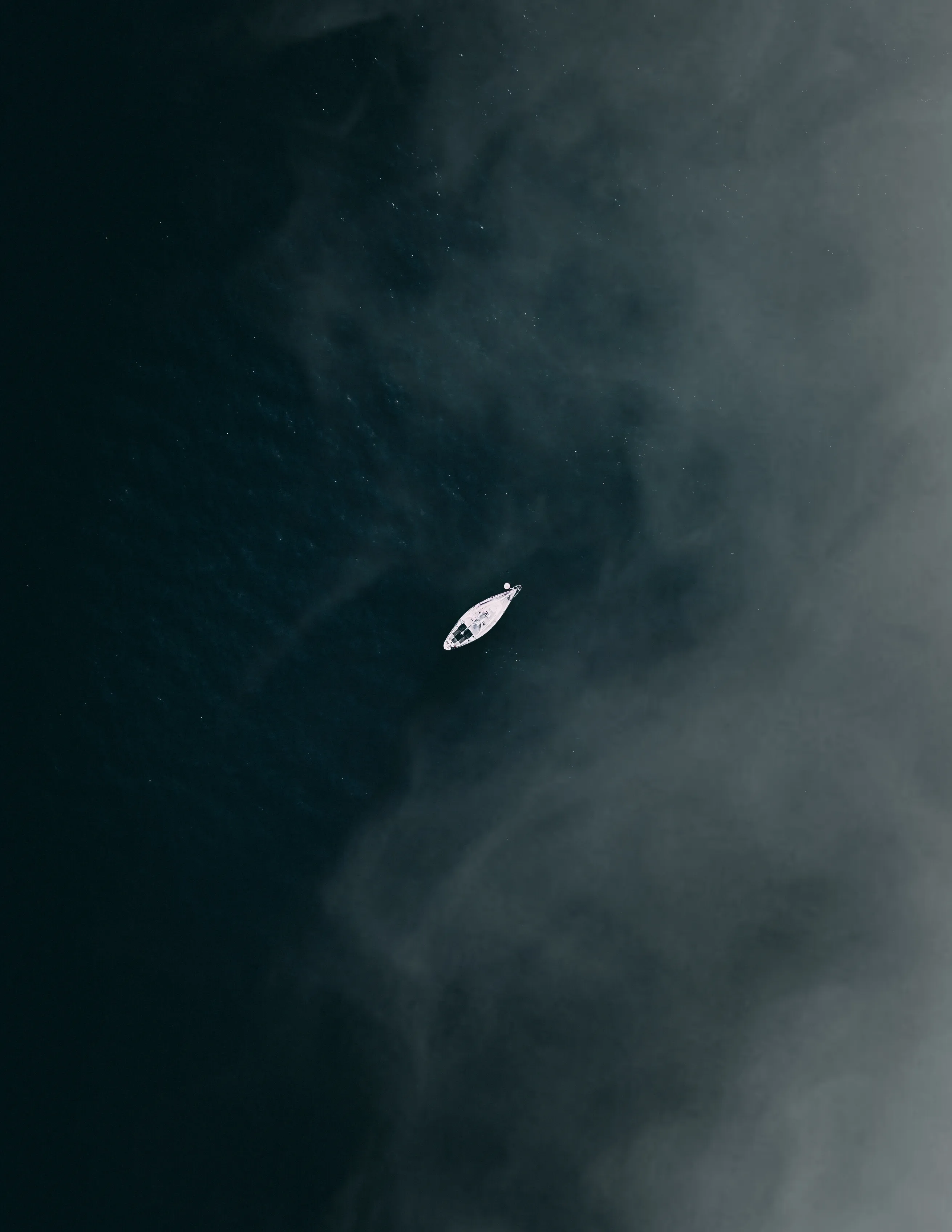 Lonely Boat Floating in Calm Waters Under Soft Mist