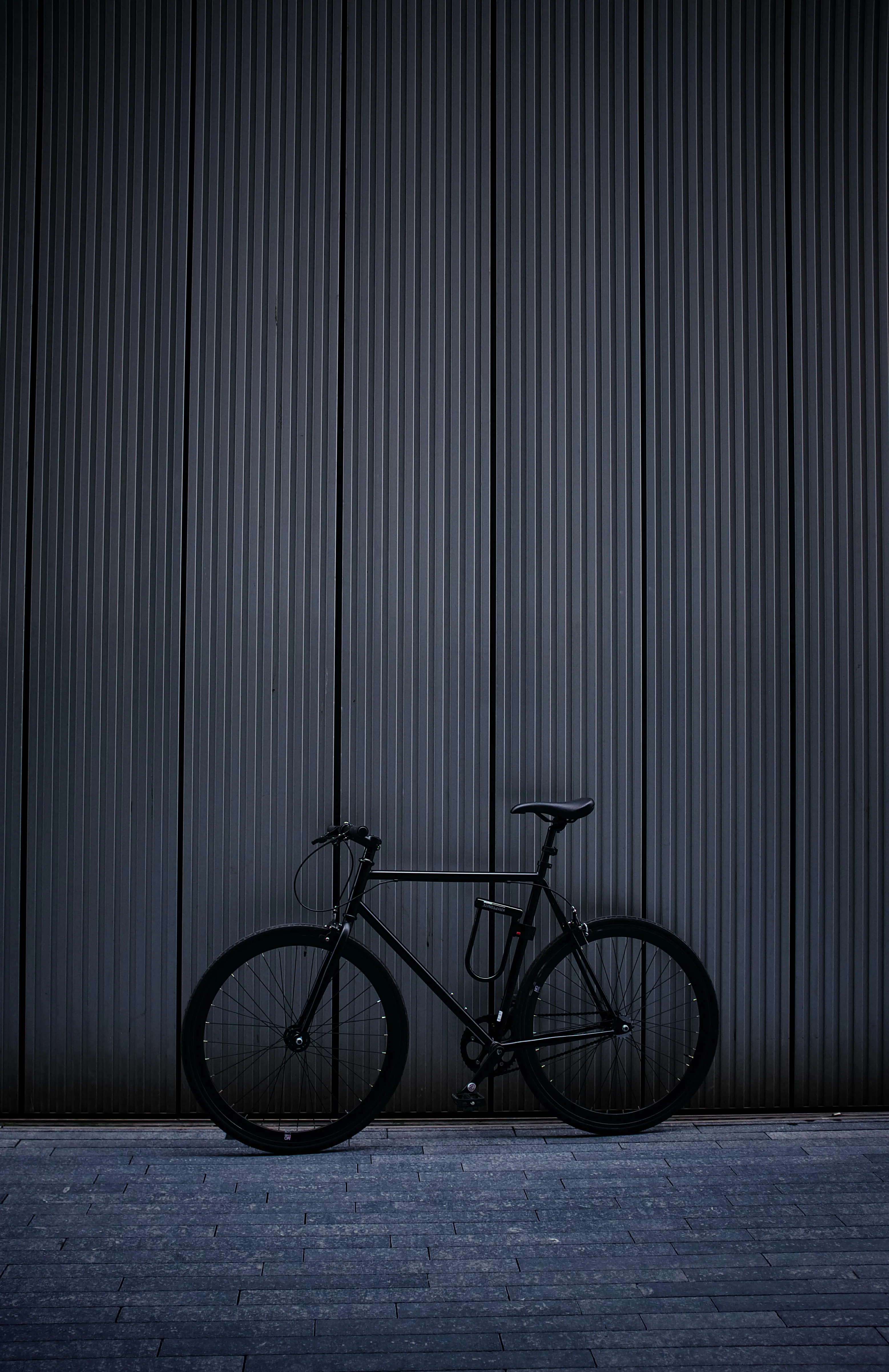 Minimal Black Bicycle Leaning Against Gray Wall Free Image