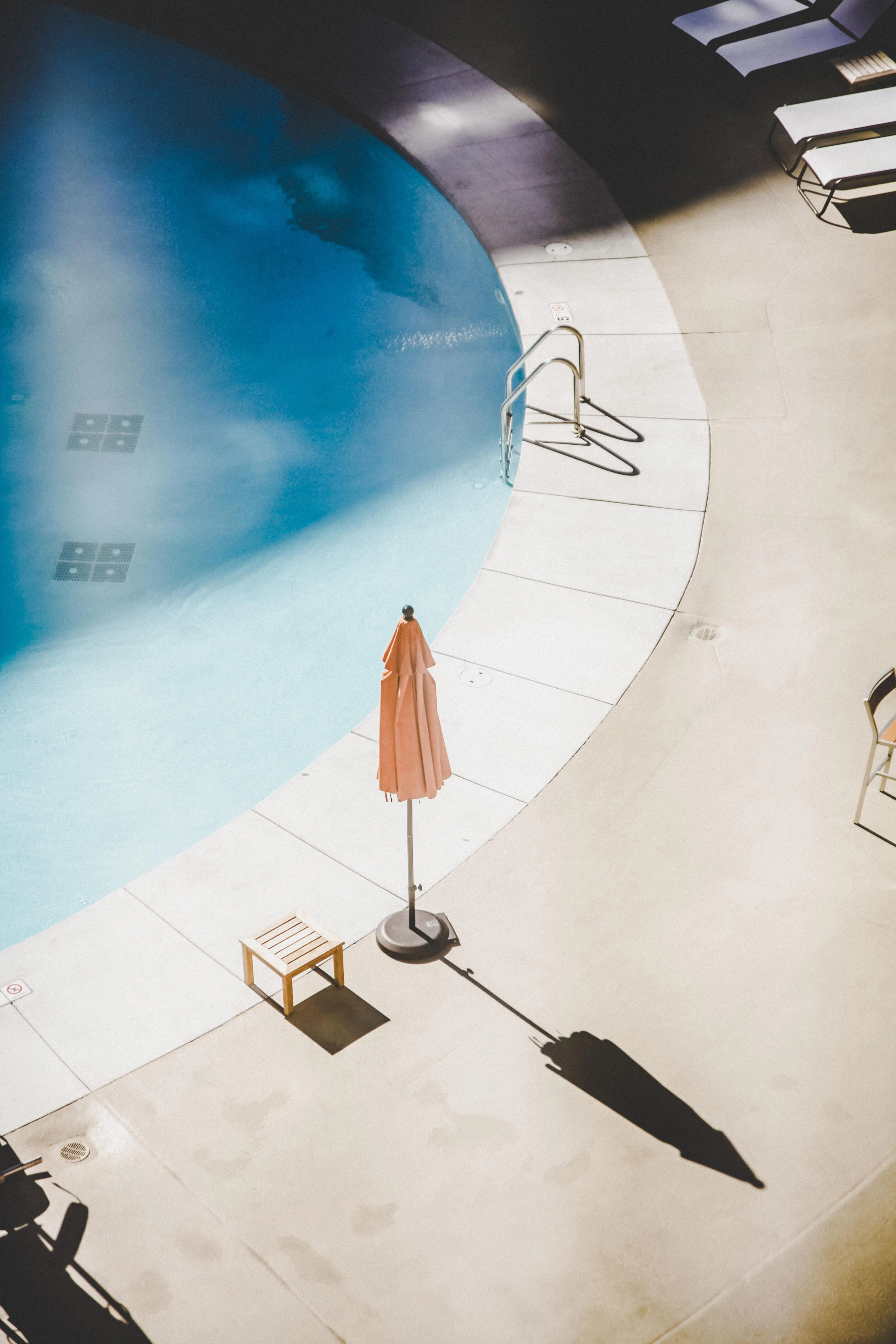 Minimalist Poolside View with Chair and Umbrella Shadows