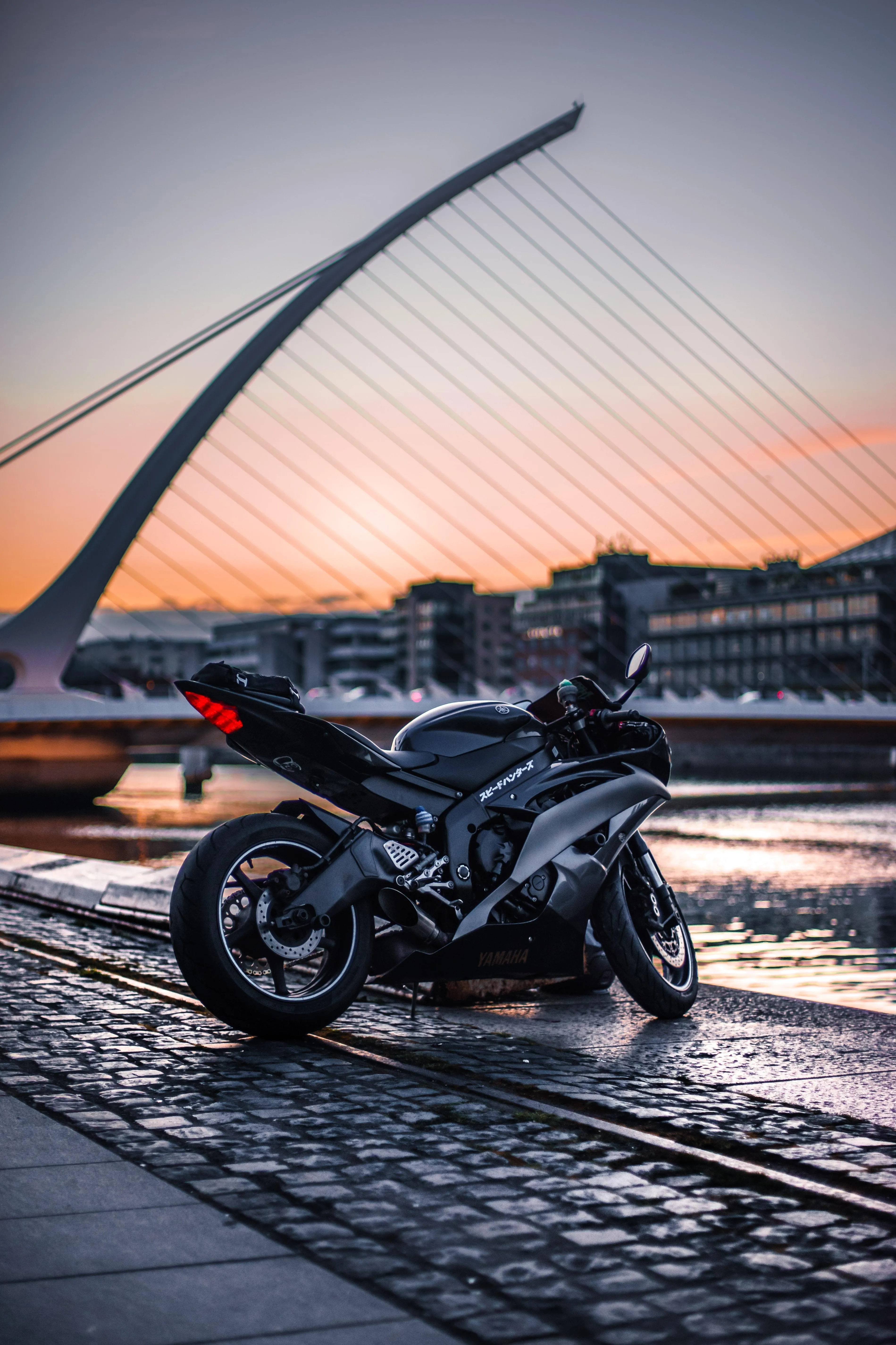 Motorcycle on Modern Bridge at Sunset with Lights Image