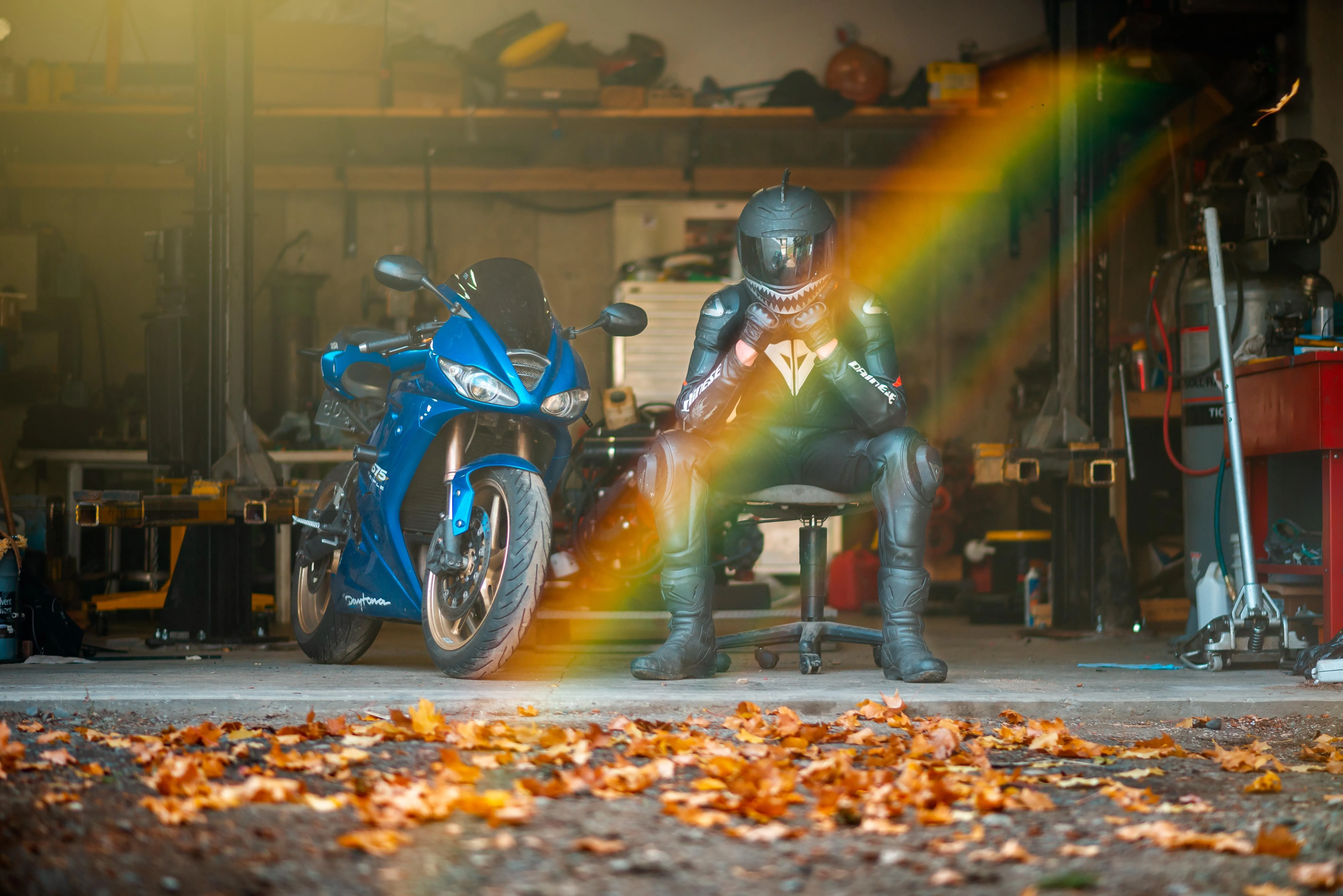 Motorcyclist in Garage with Blue Bike and Autumn Leaves Scene