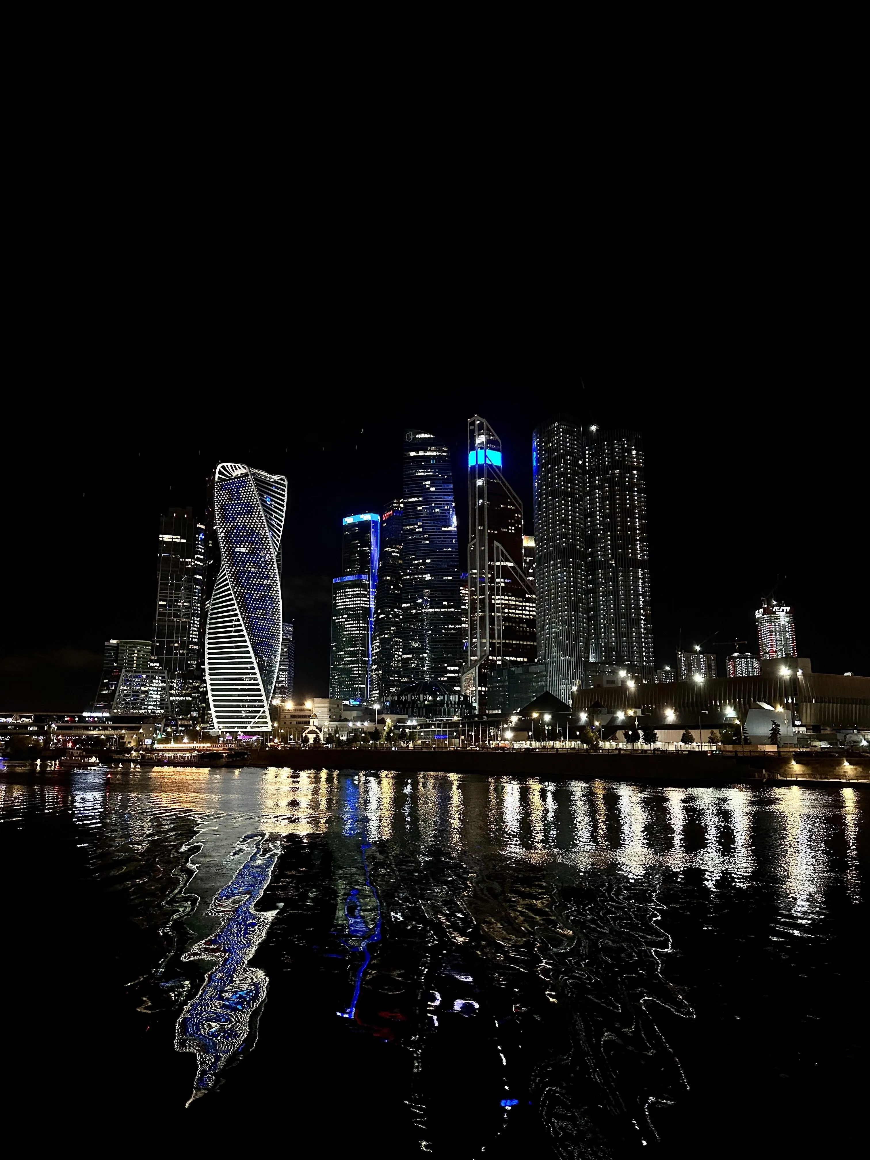 Nighttime City Skyline Reflected on Calm Water Surface