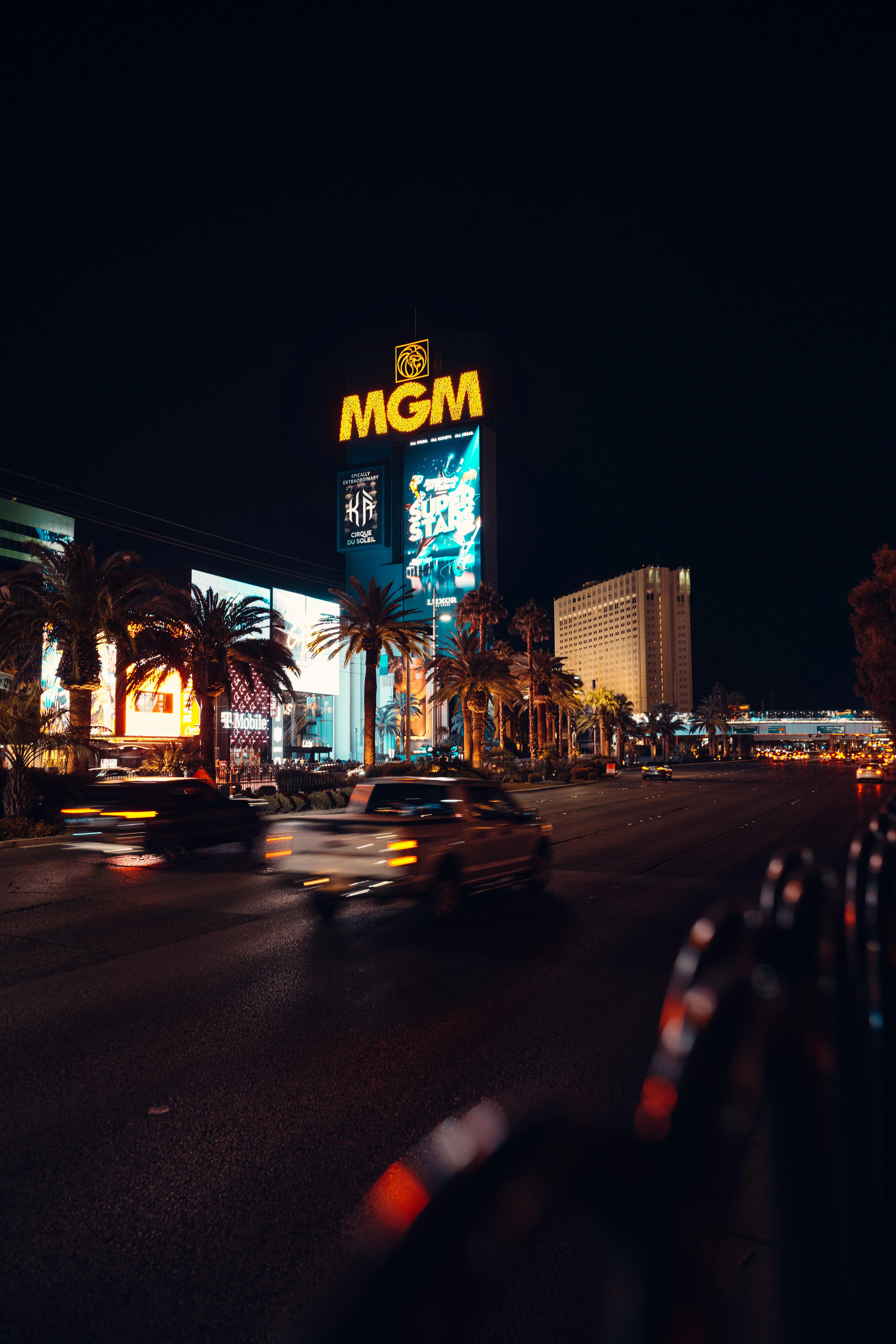 Nighttime City Street with Neon Lights and Cars Wallpaper