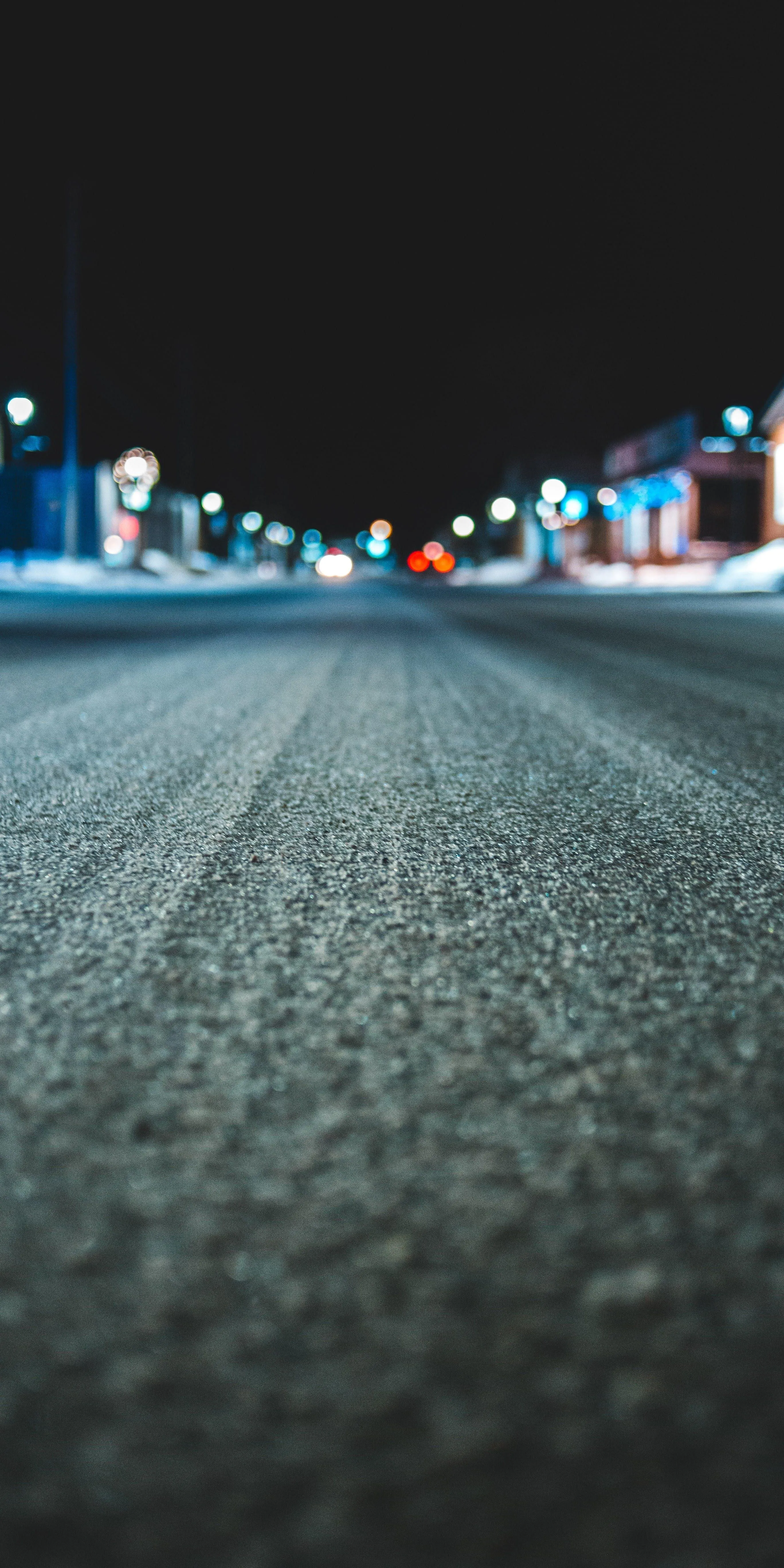 Nighttime Road with Blurred City Lights and Asphalt Focus