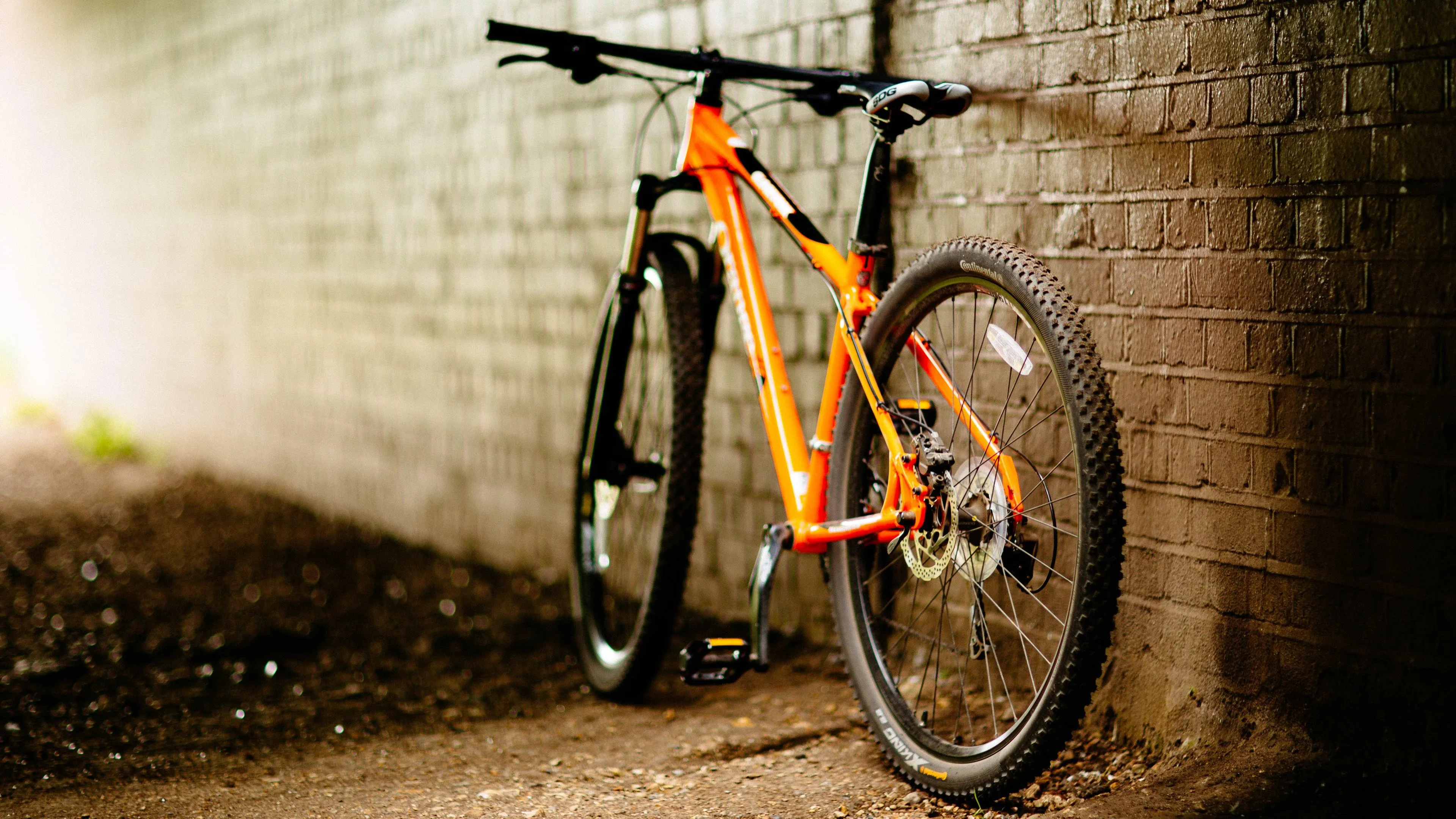 Orange Bicycle Parked Against Brick Wall with Warm Lighting