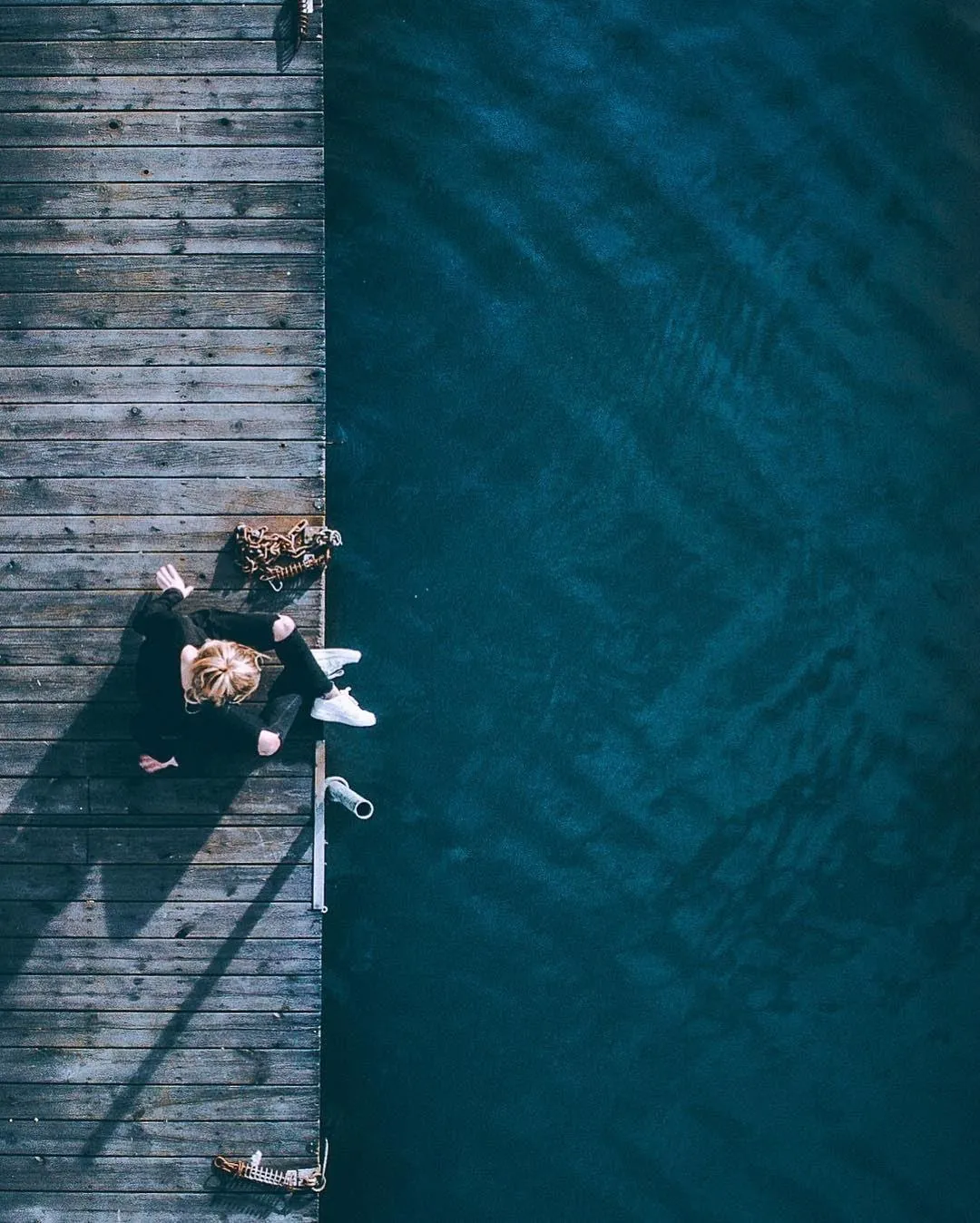 Overhead Shot of Man Sitting on Pier with Calm Water View
