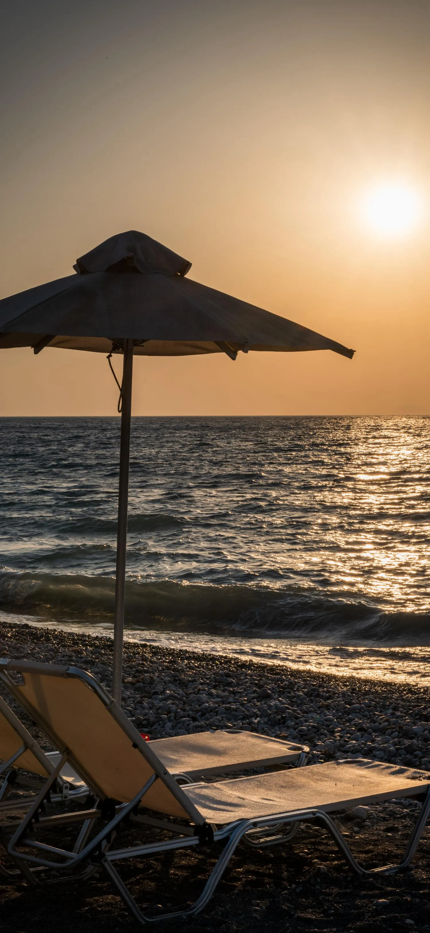 Peaceful Beach Sunset with Umbrella and Chair Wallpaper