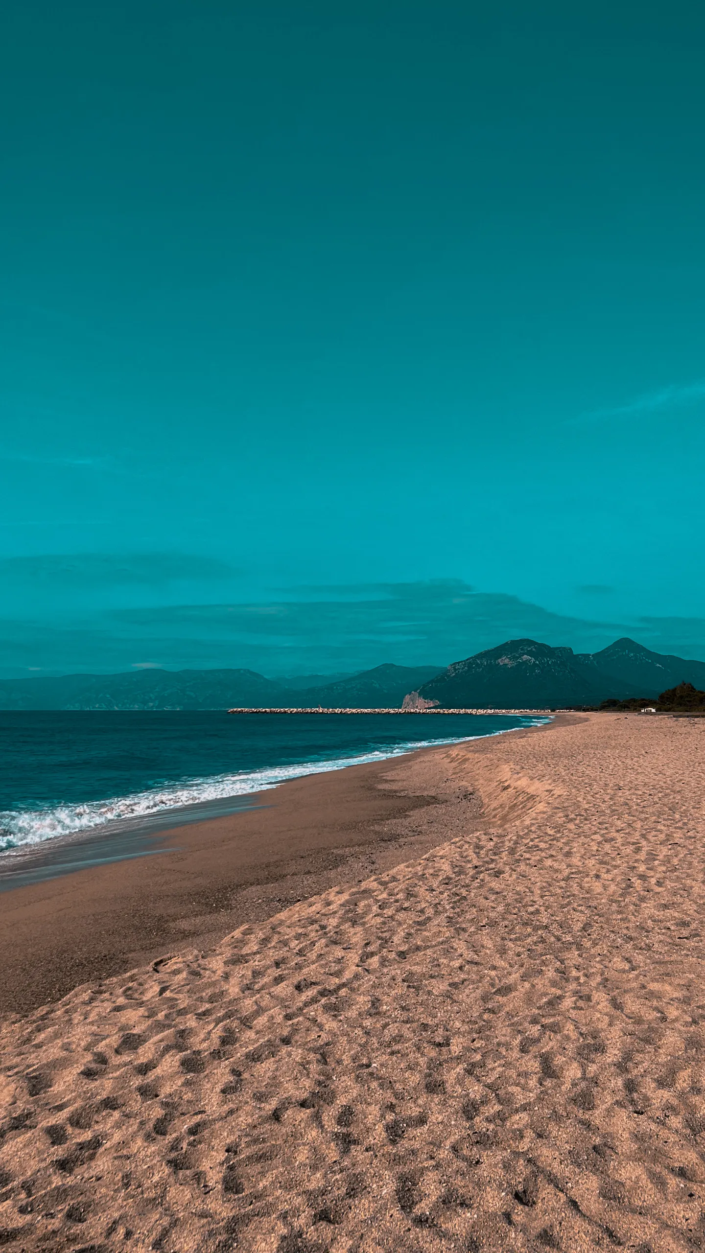 Peaceful Sandy Beach with Calm Blue Sea and Mountains