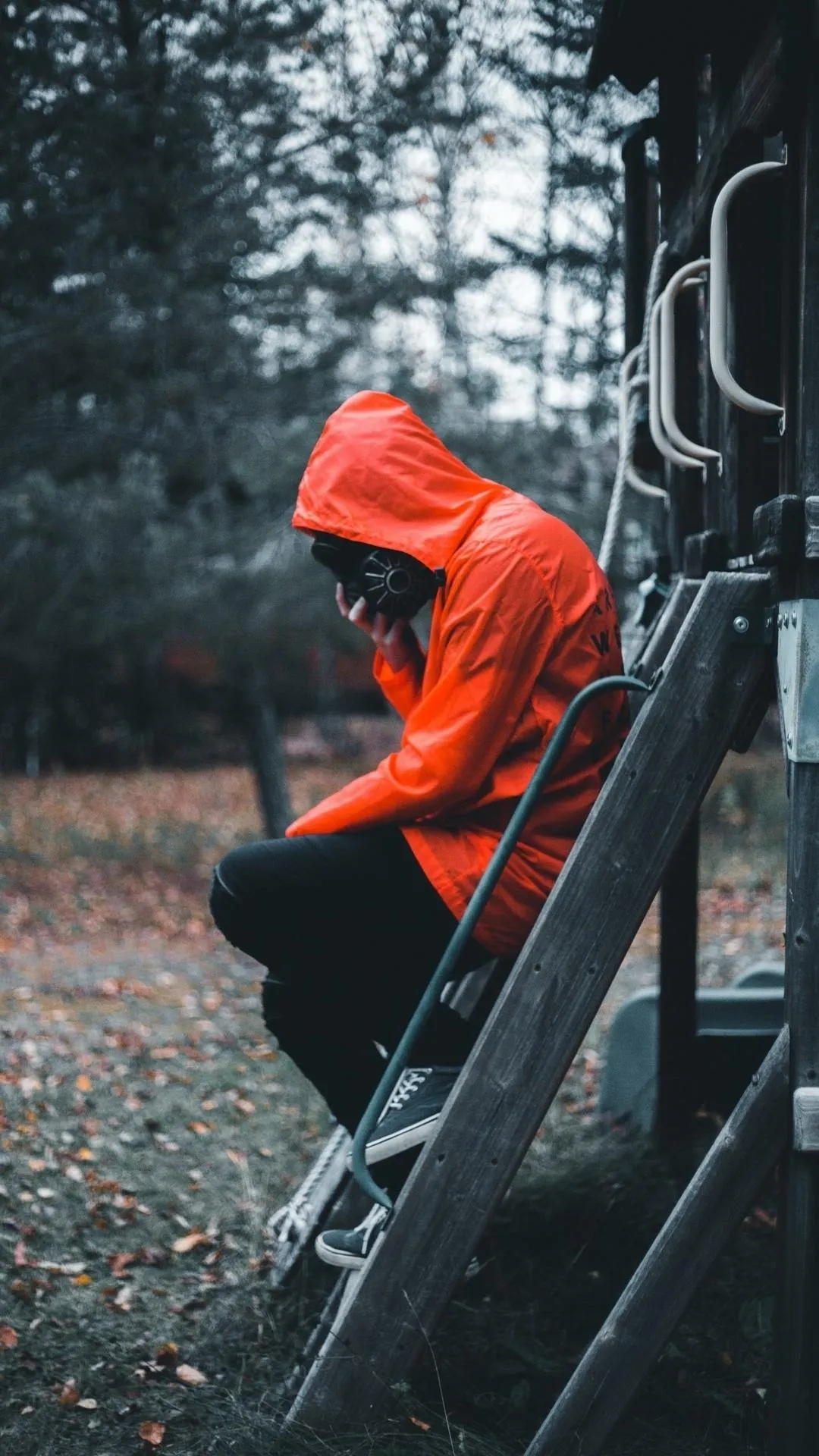 Person in Orange Jacket Sitting Thoughtfully Outdoors