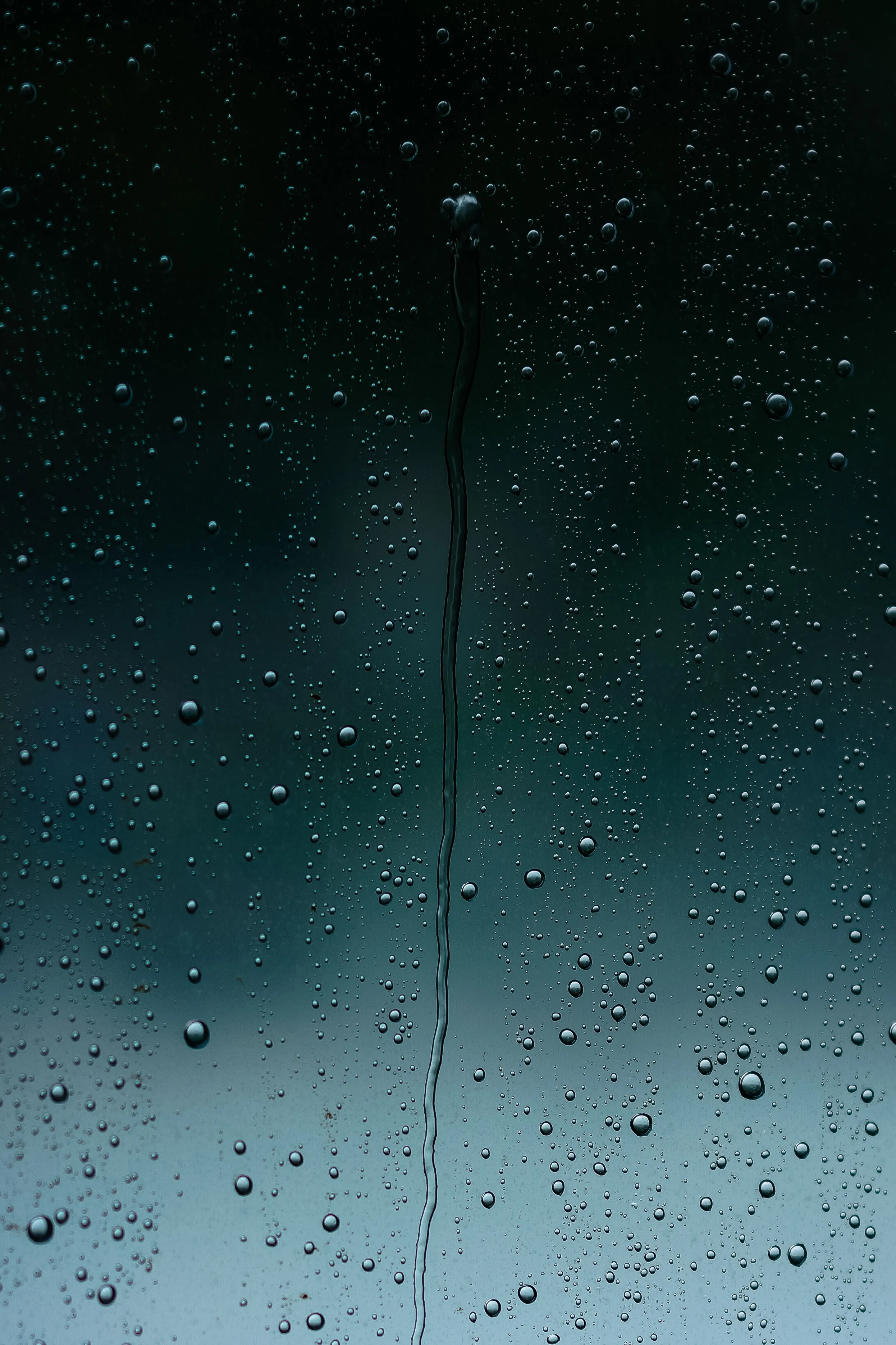 Raindrops on Glass Window Under Cloudy Night Sky Wallpaper