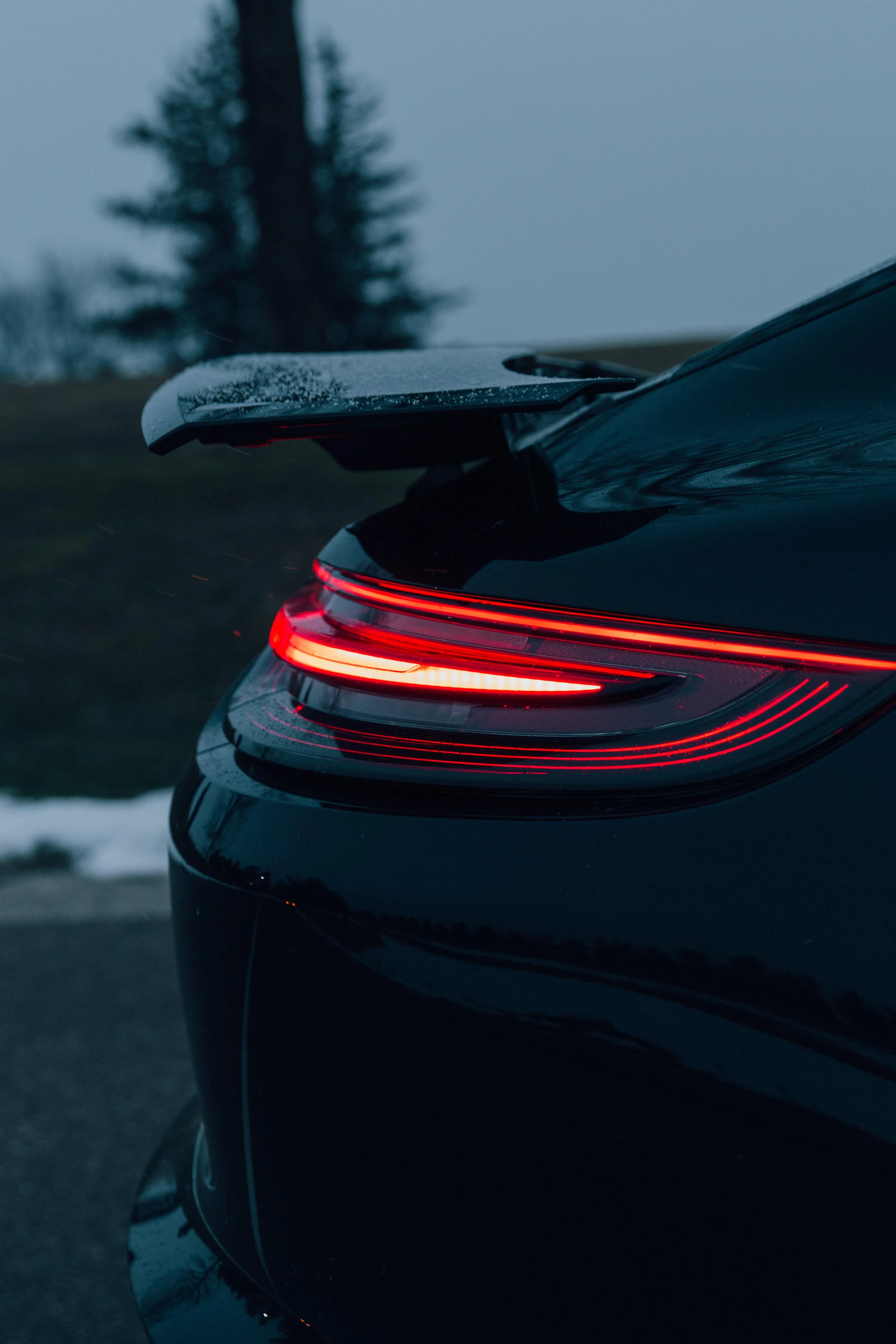 Rear View of Luxury Car with Red Taillights in Snow Wallpaper