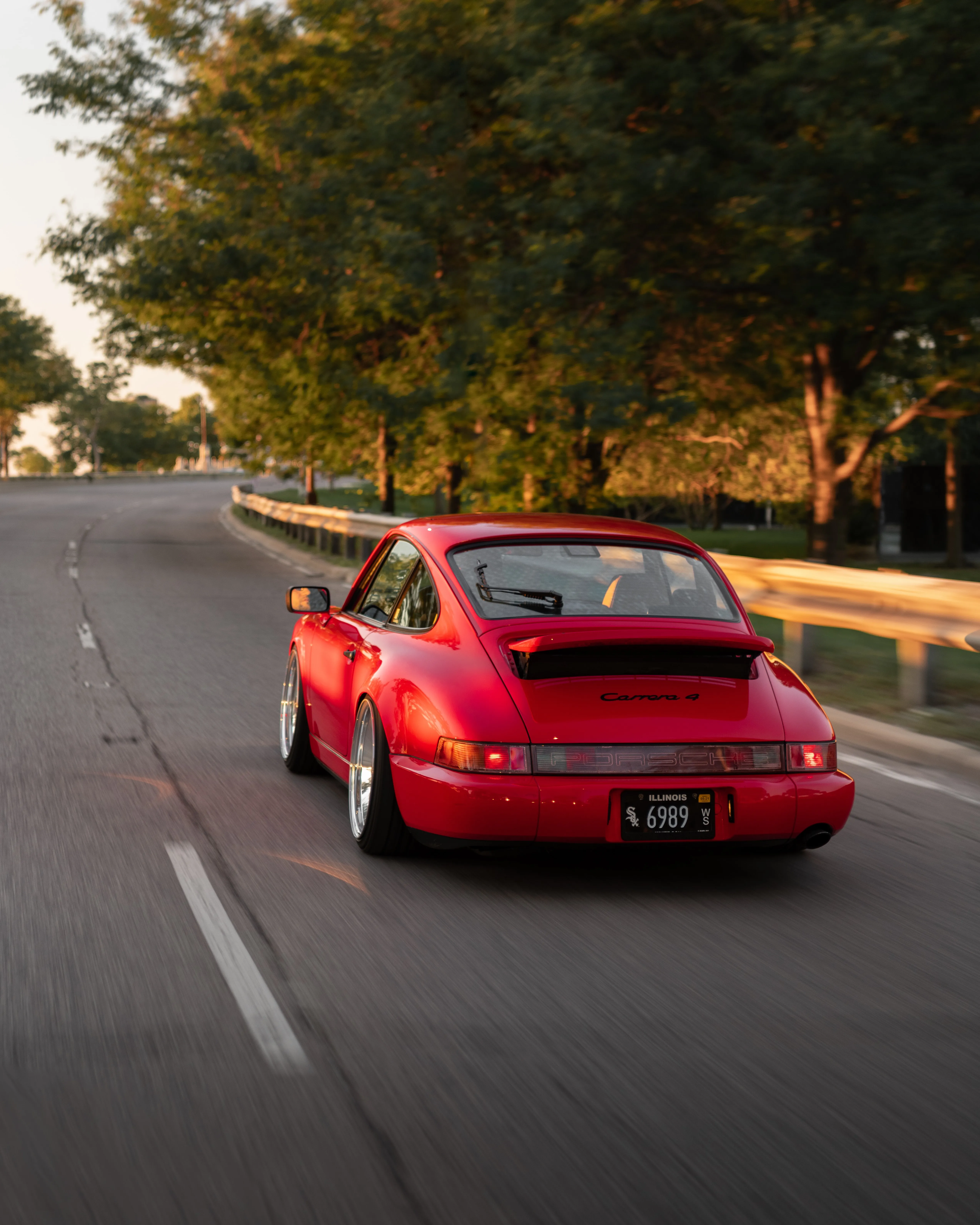 Red Sports Car Driving Down Tree Lined Suburban Road
