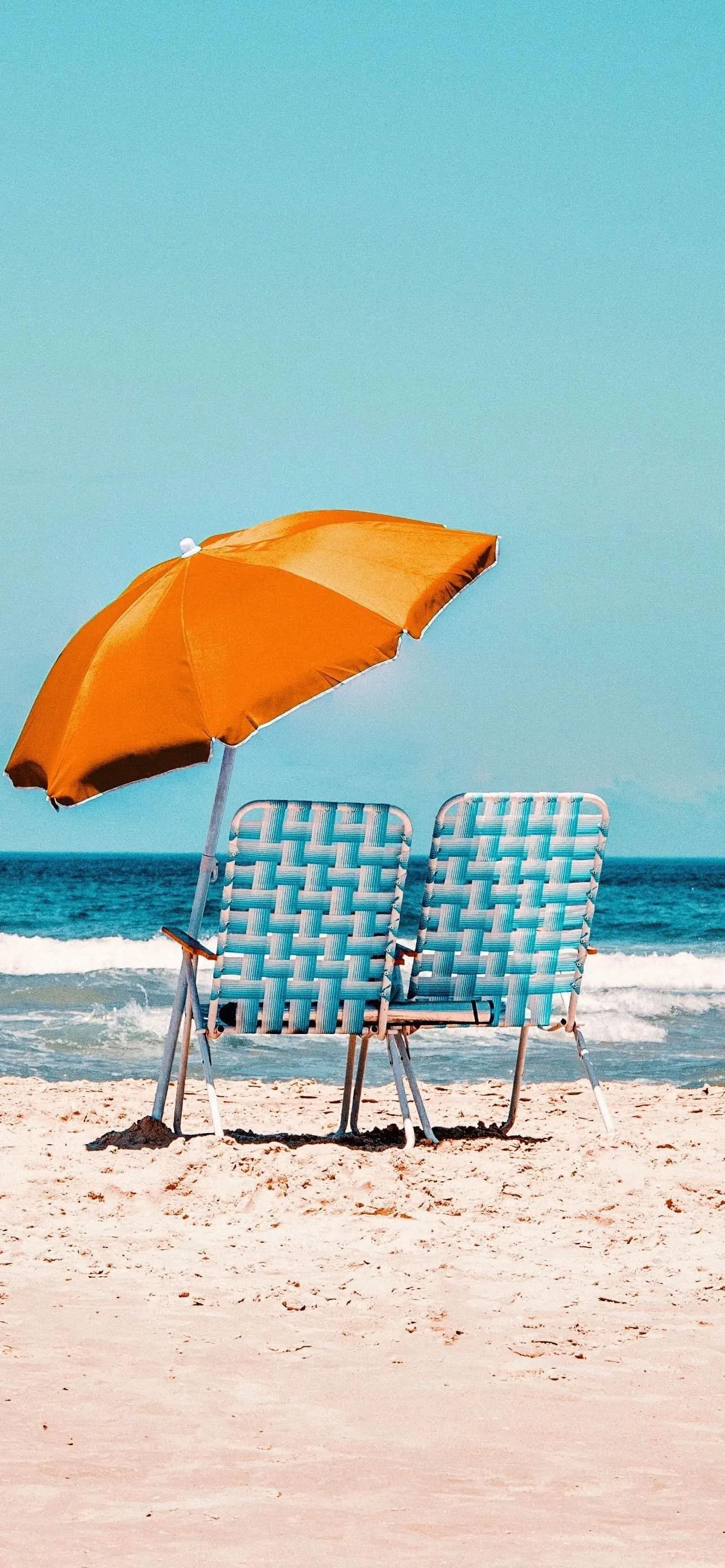 Relaxing Beach Scene with Orange Umbrella and Chairs
