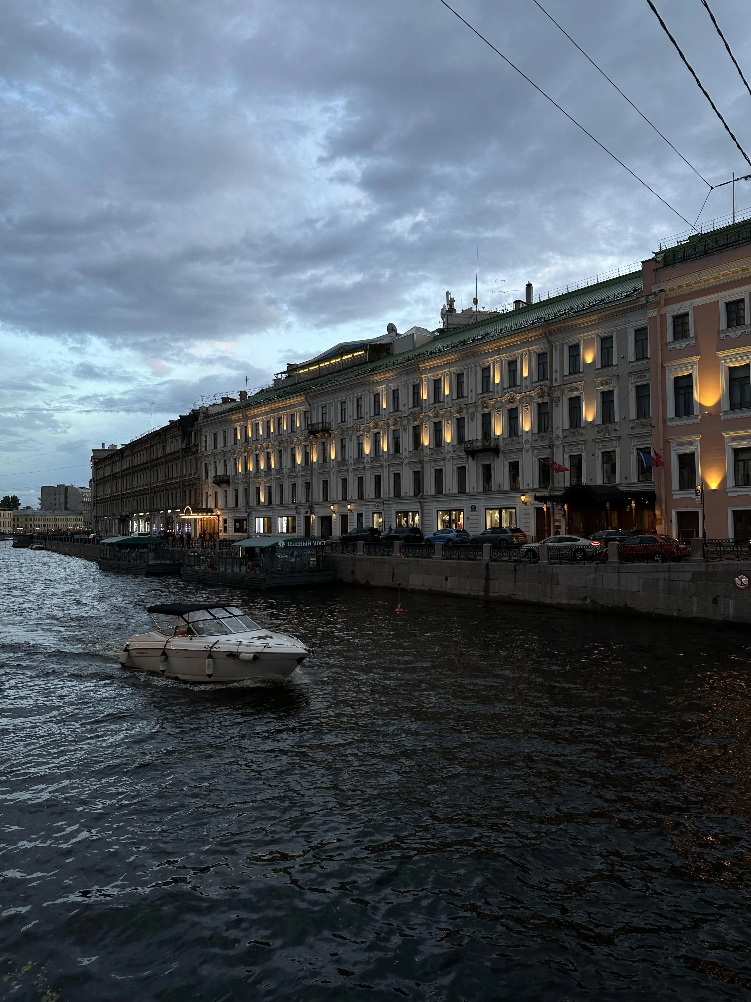 Riverfront Cityscape with Boats and Overcast Skies Wallpaper