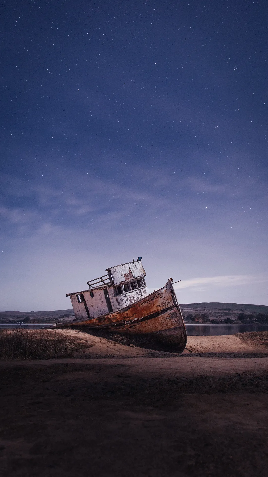 Rusted Abandoned Shipwreck on Sandy Beach at Dusk Image