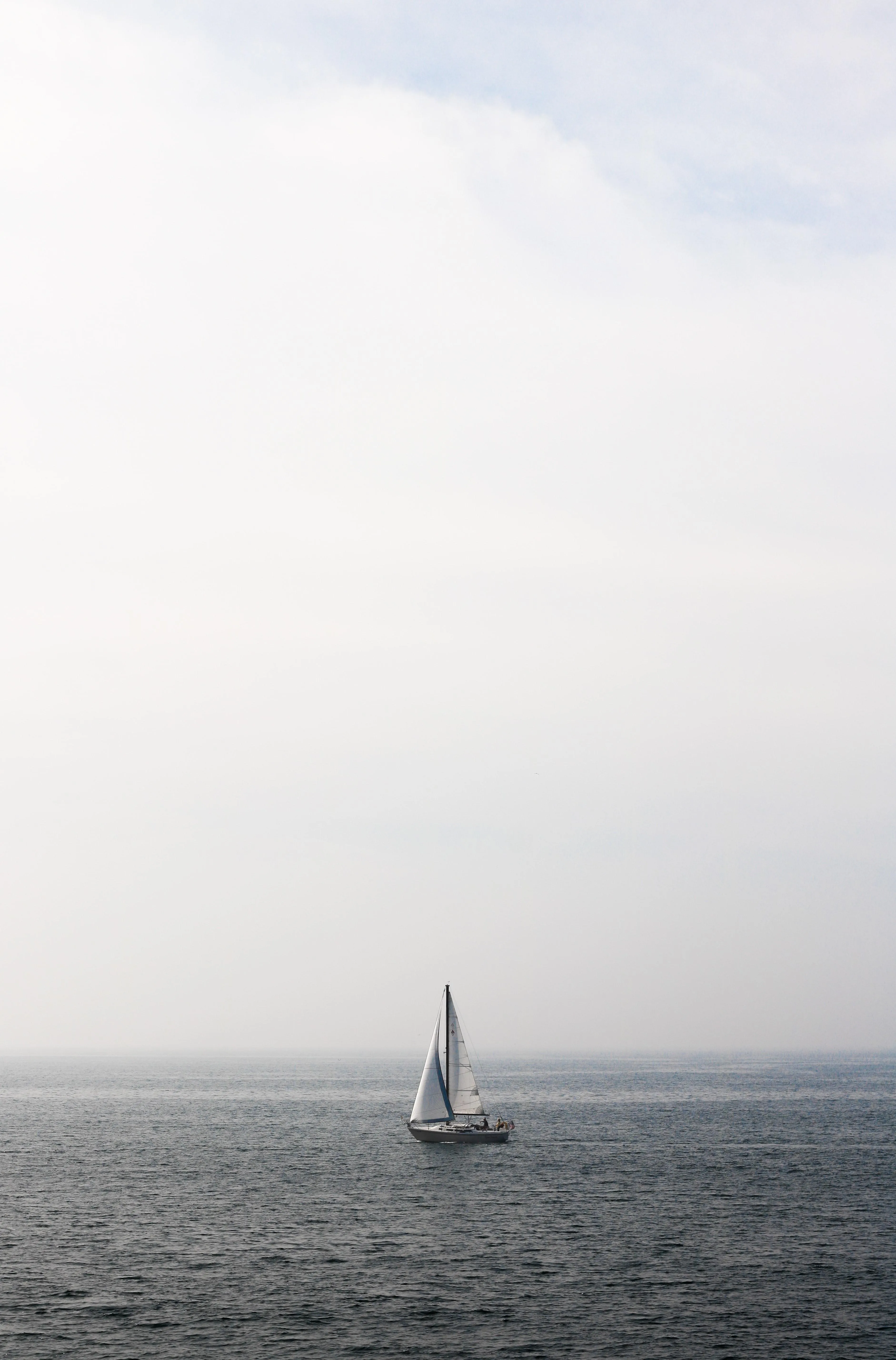 Sailboat on Calm Sea Under Clear Morning Sky Wallpaper