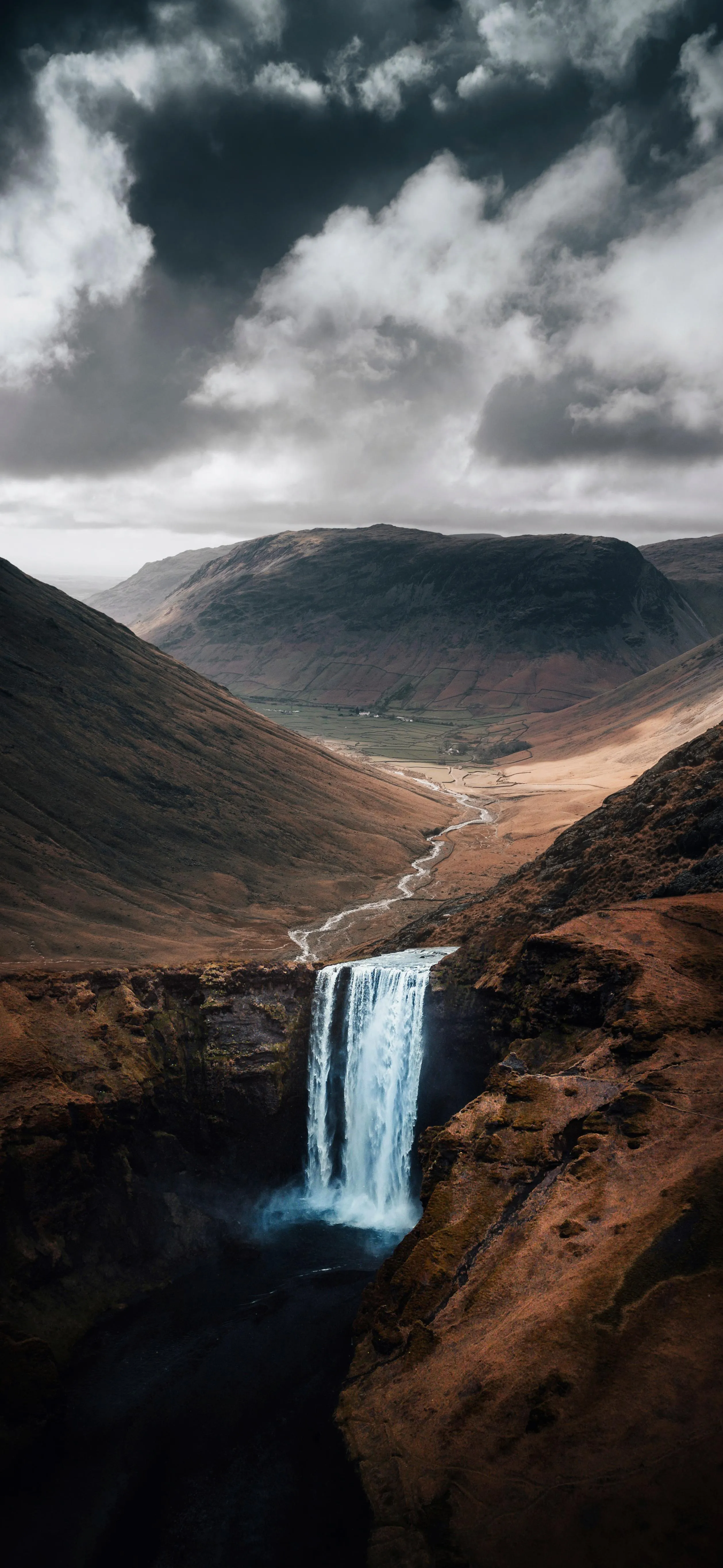 Scenic Waterfall Flowing Down Rocky Hills in Moody Light