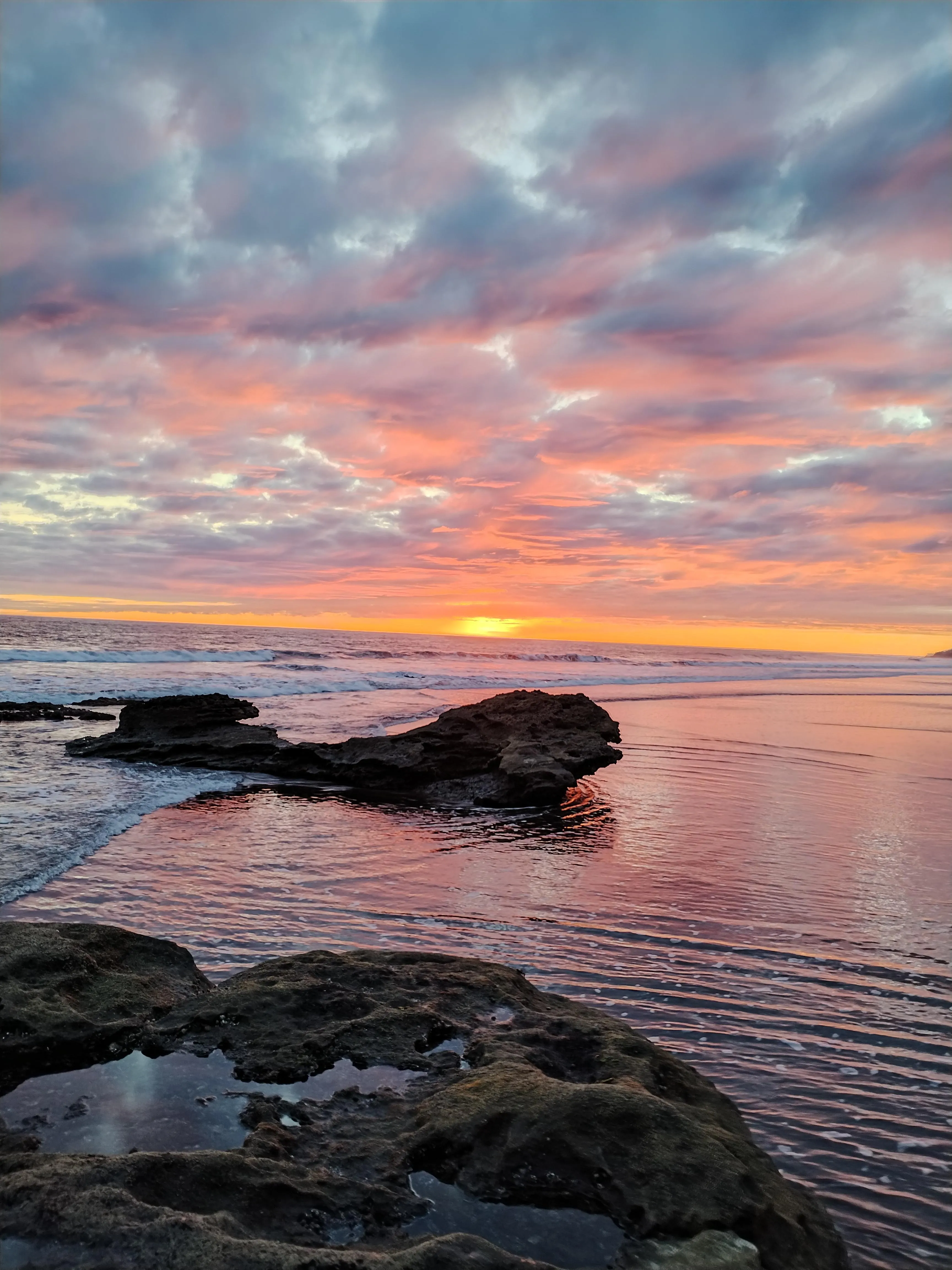Serene Ocean Sunset Over Rocky Shore with Vivid Colors