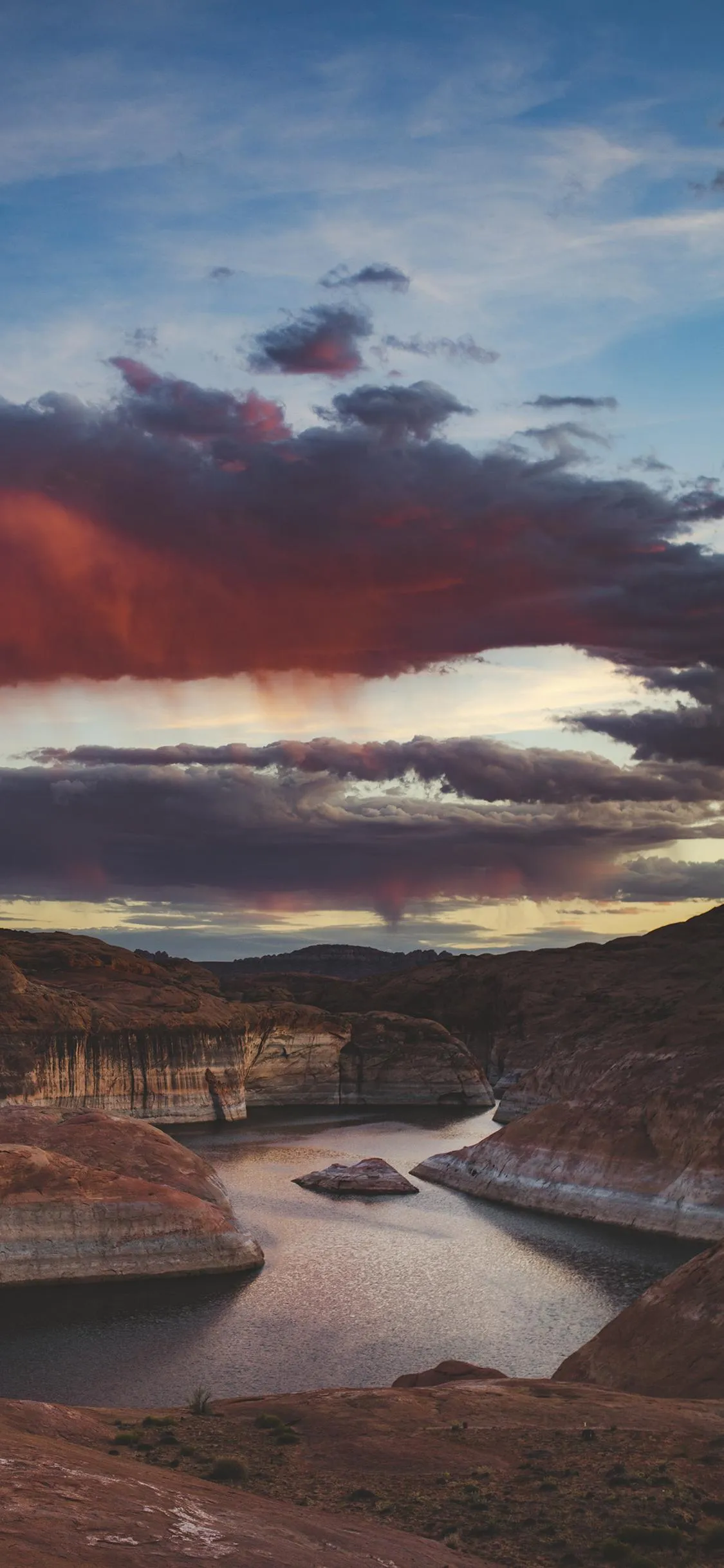 Serene Sunset Over Rocky Shore and Calm Waters Wallpaper