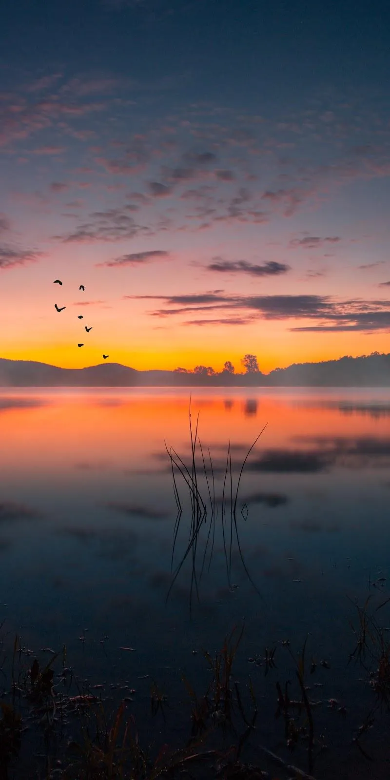 Serene Sunset View Over Calm Water Reflections Wallpaper