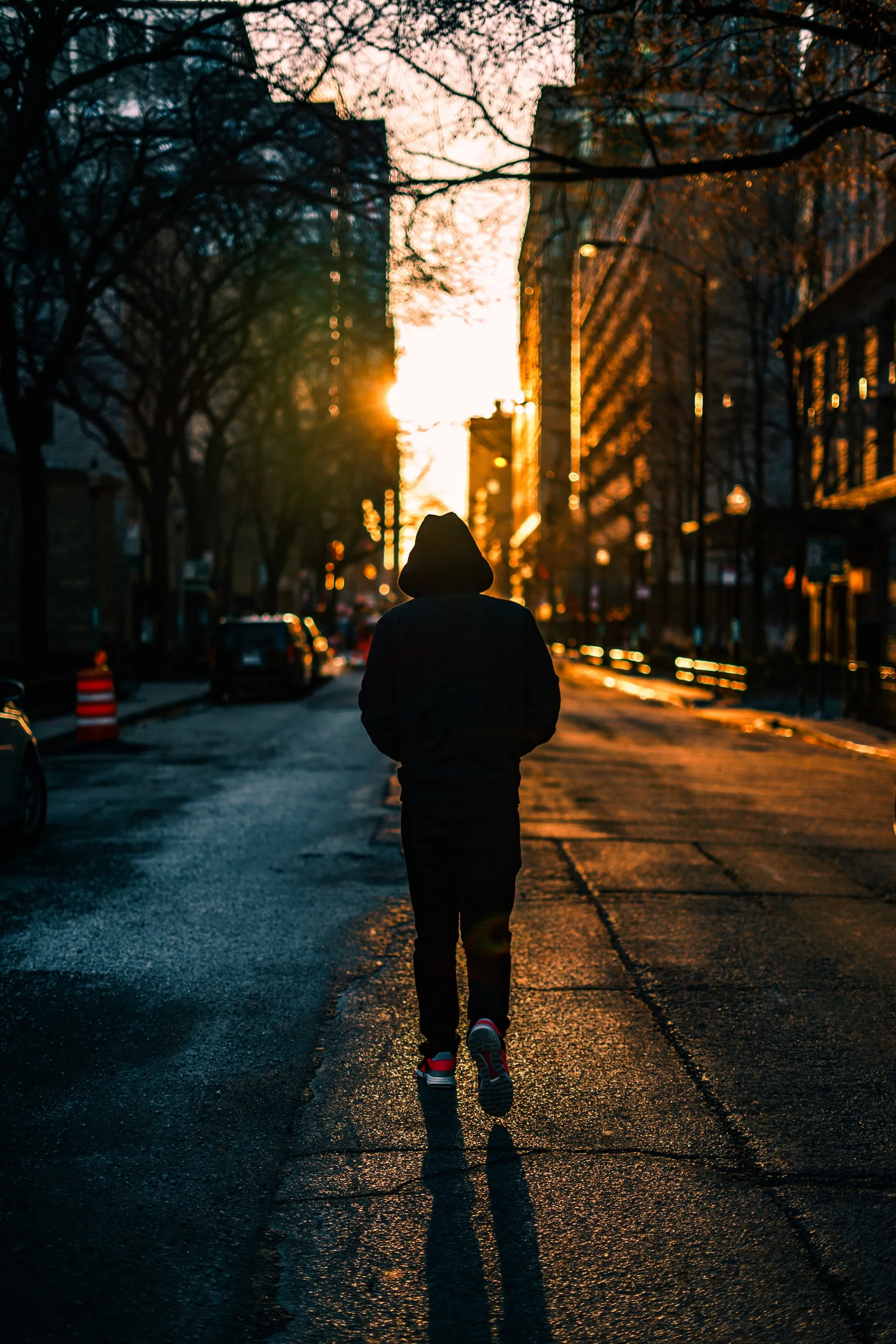 Silhouette of Person Walking on City Street at Sunset