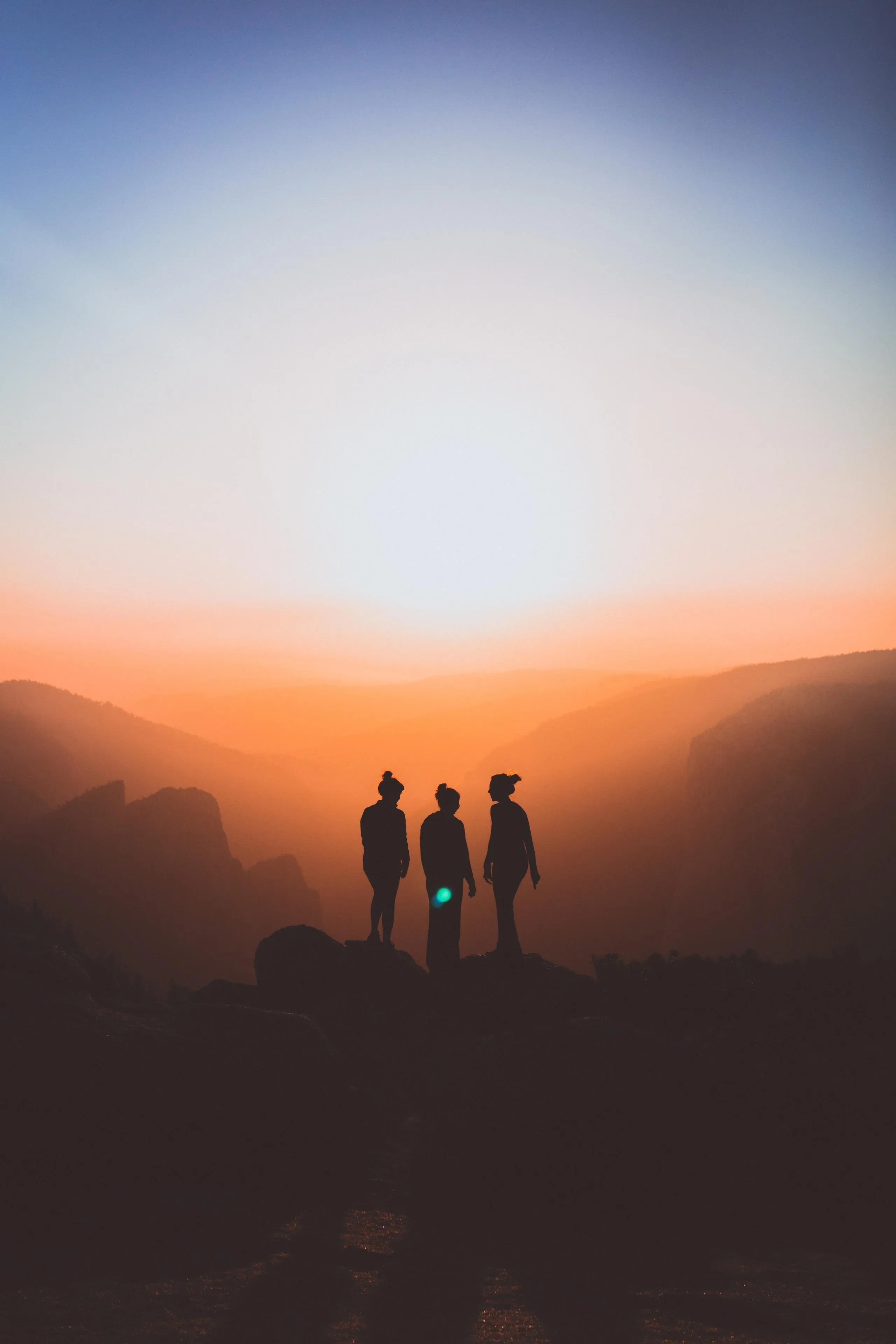 Silhouetted People Watching Sunrise Over Misty Mountains