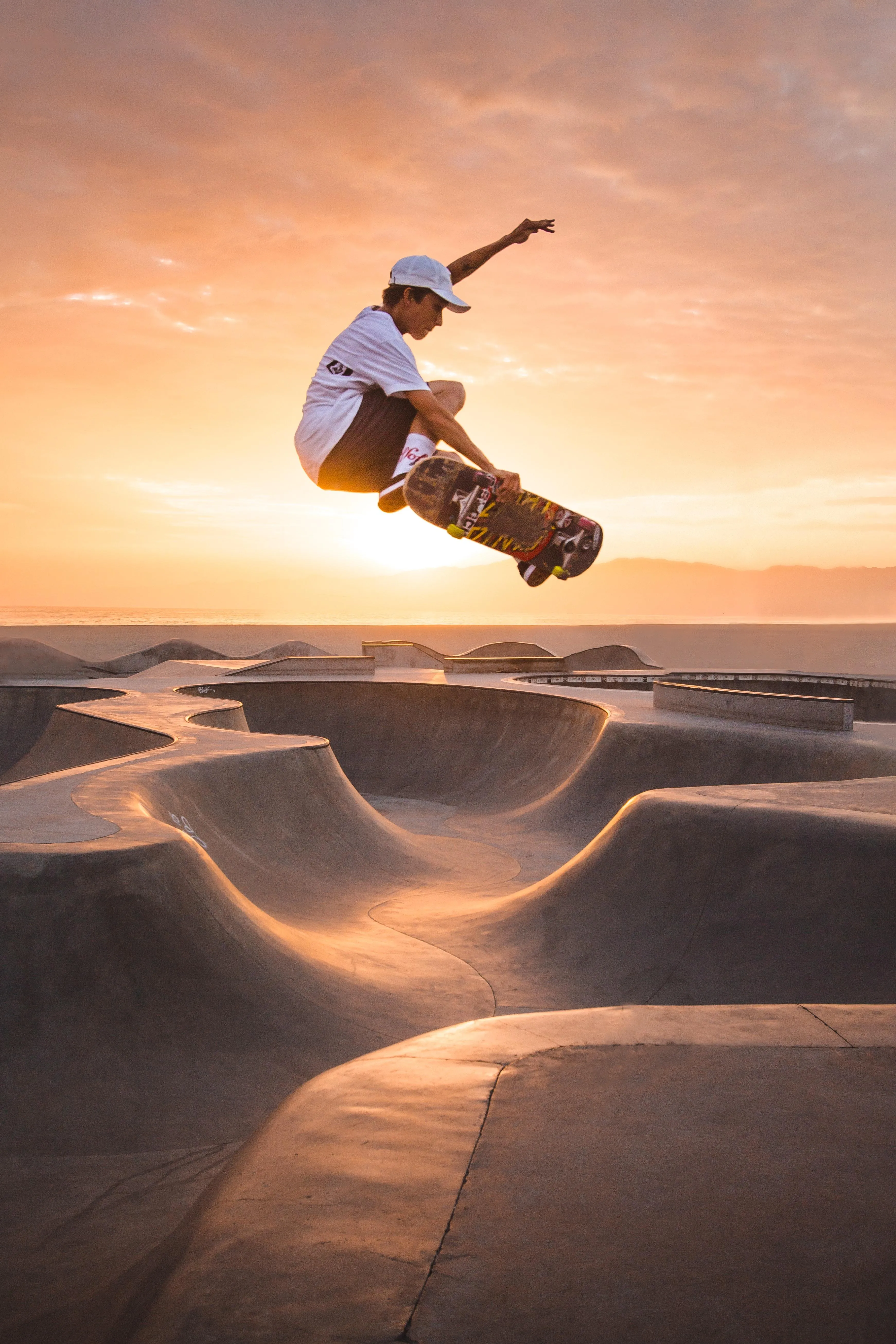Skateboarder Performing an Aerial Trick at Sunset Skatepark