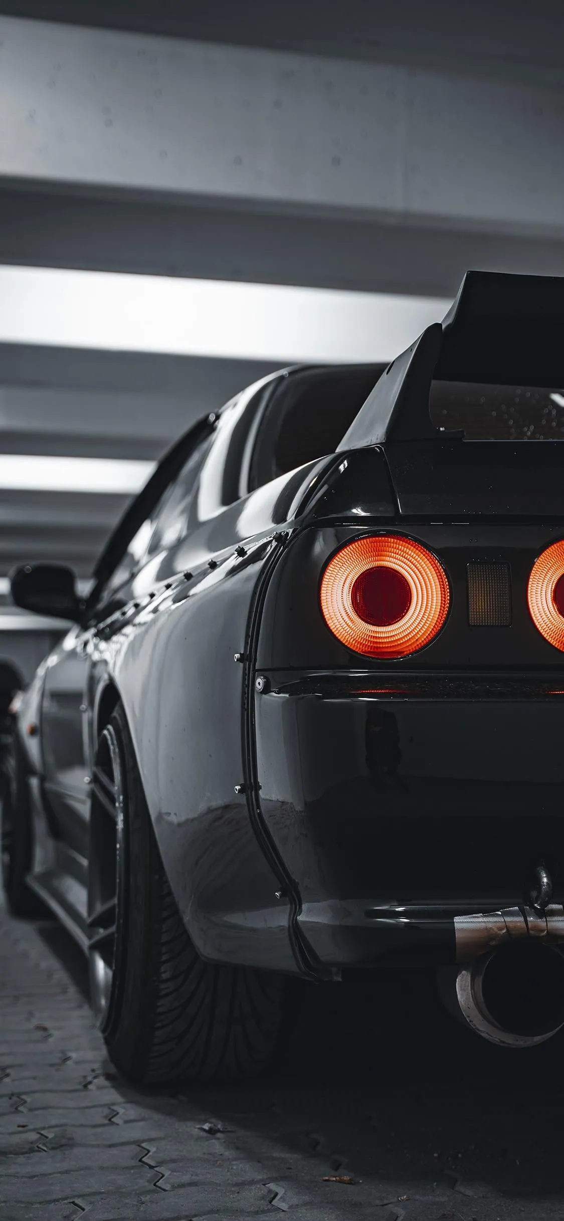 Sleek Black Car Rear View with Orange Tail Lights Wallpaper