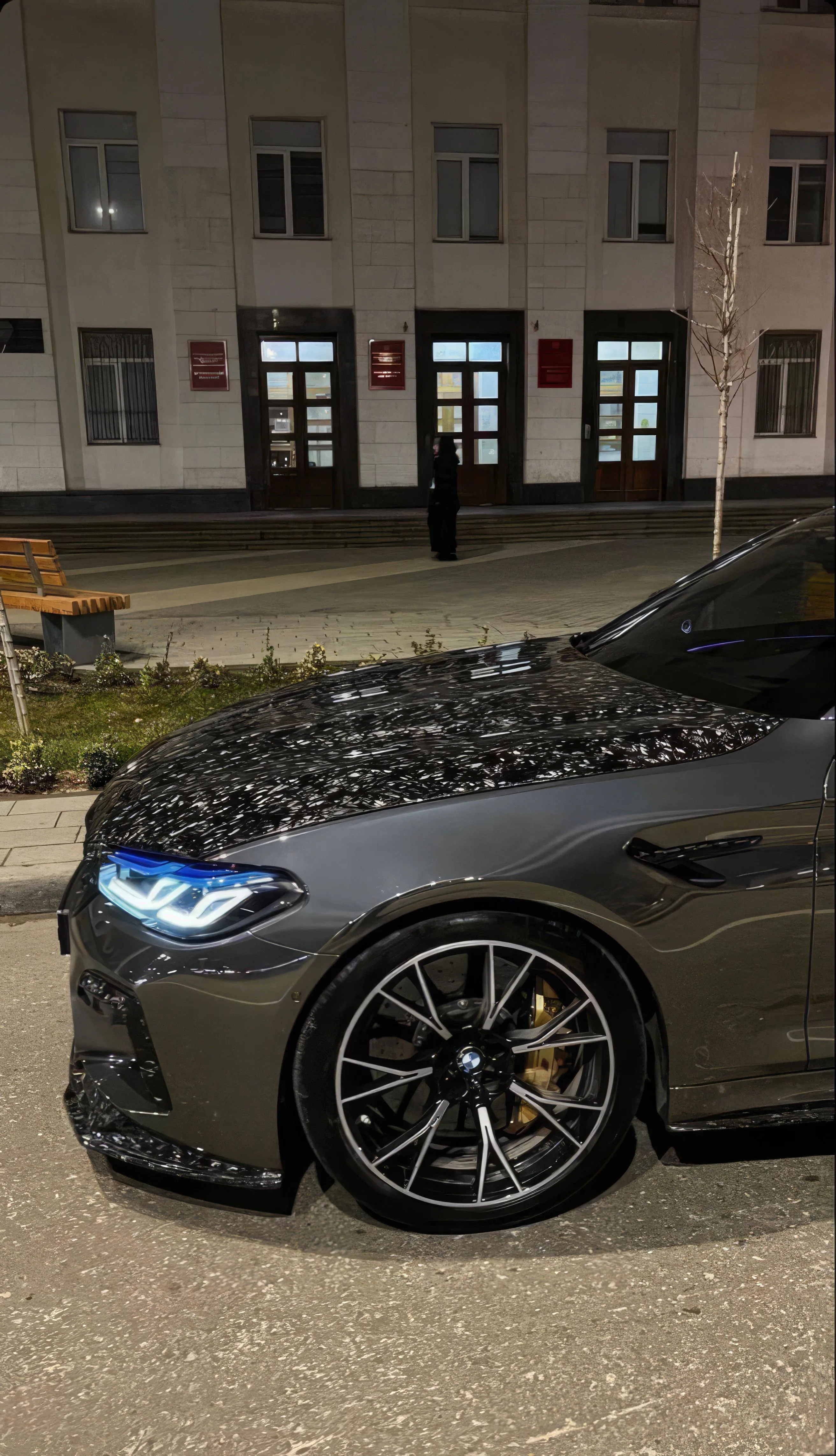 Sleek Black Sports Car Parked in Front of Building Wallpaper