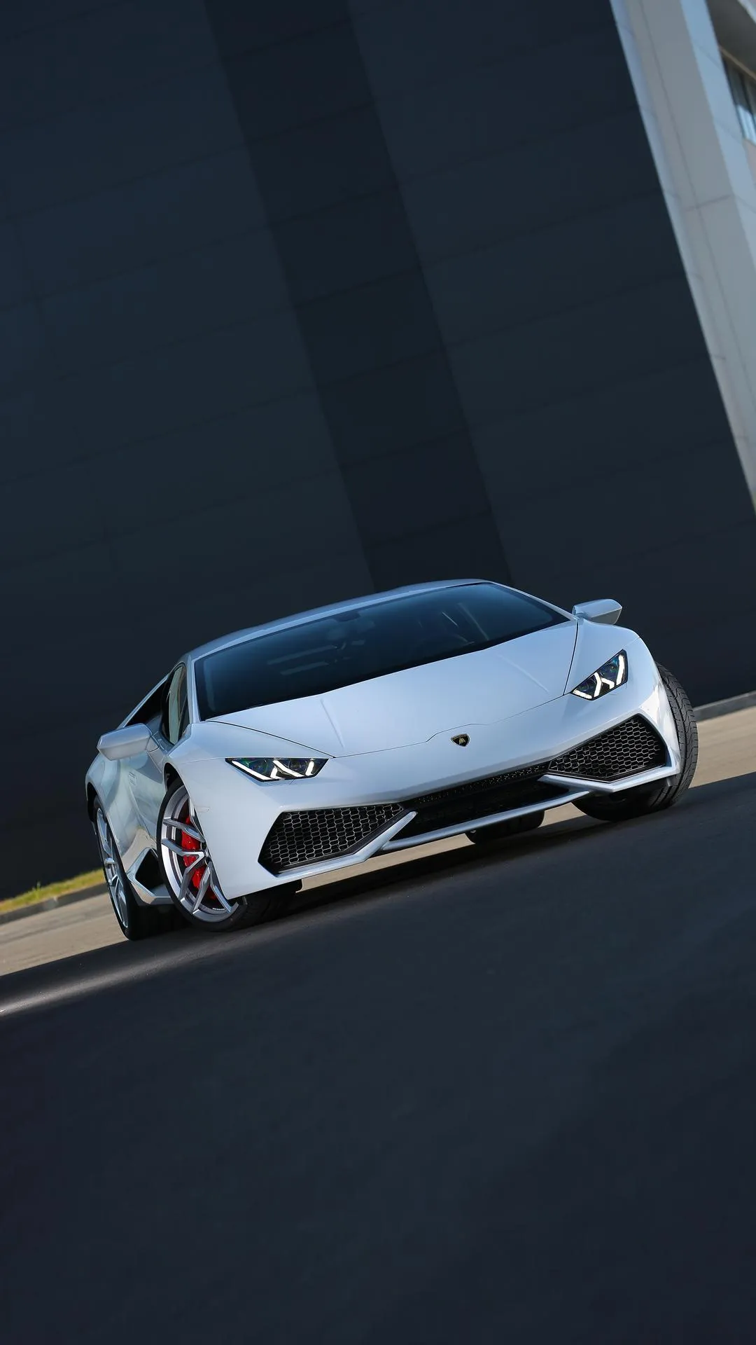 Sleek White Supercar Driving Through Urban Curve Wallpaper