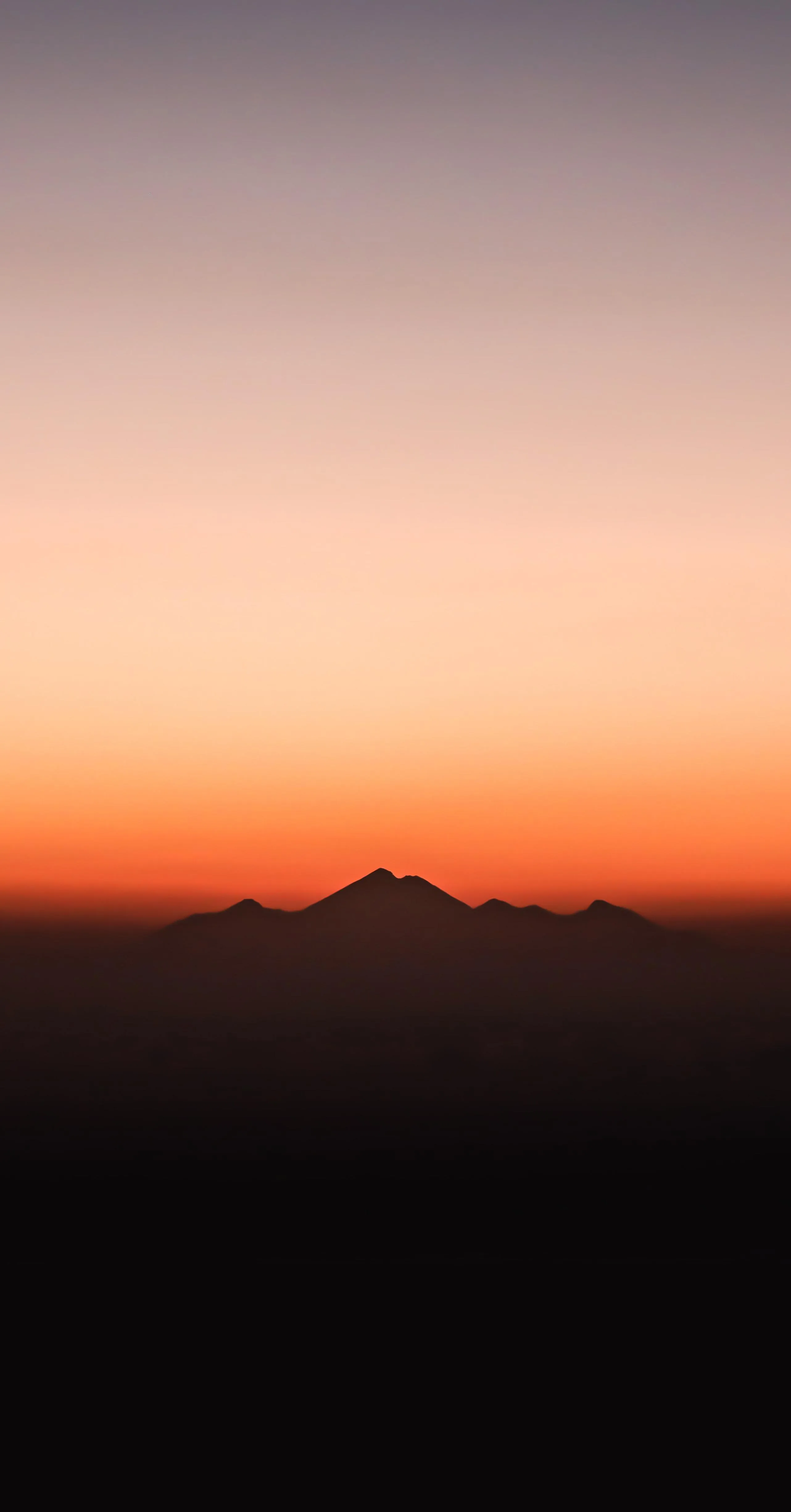 Soft Gradient Sunset Over Distant Mountain Range Wallpaper