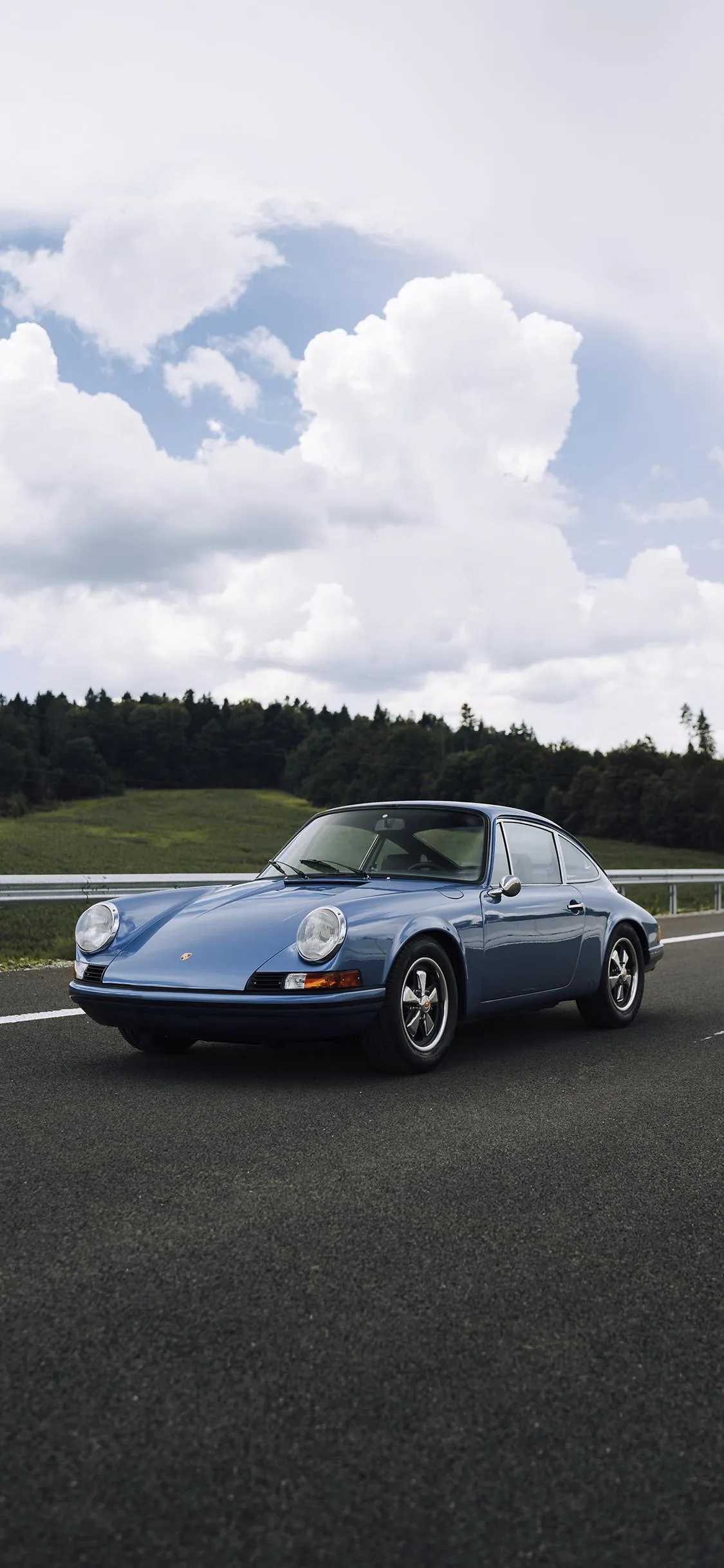 Sports Car Driving on Open Road Under Cloudy Skies