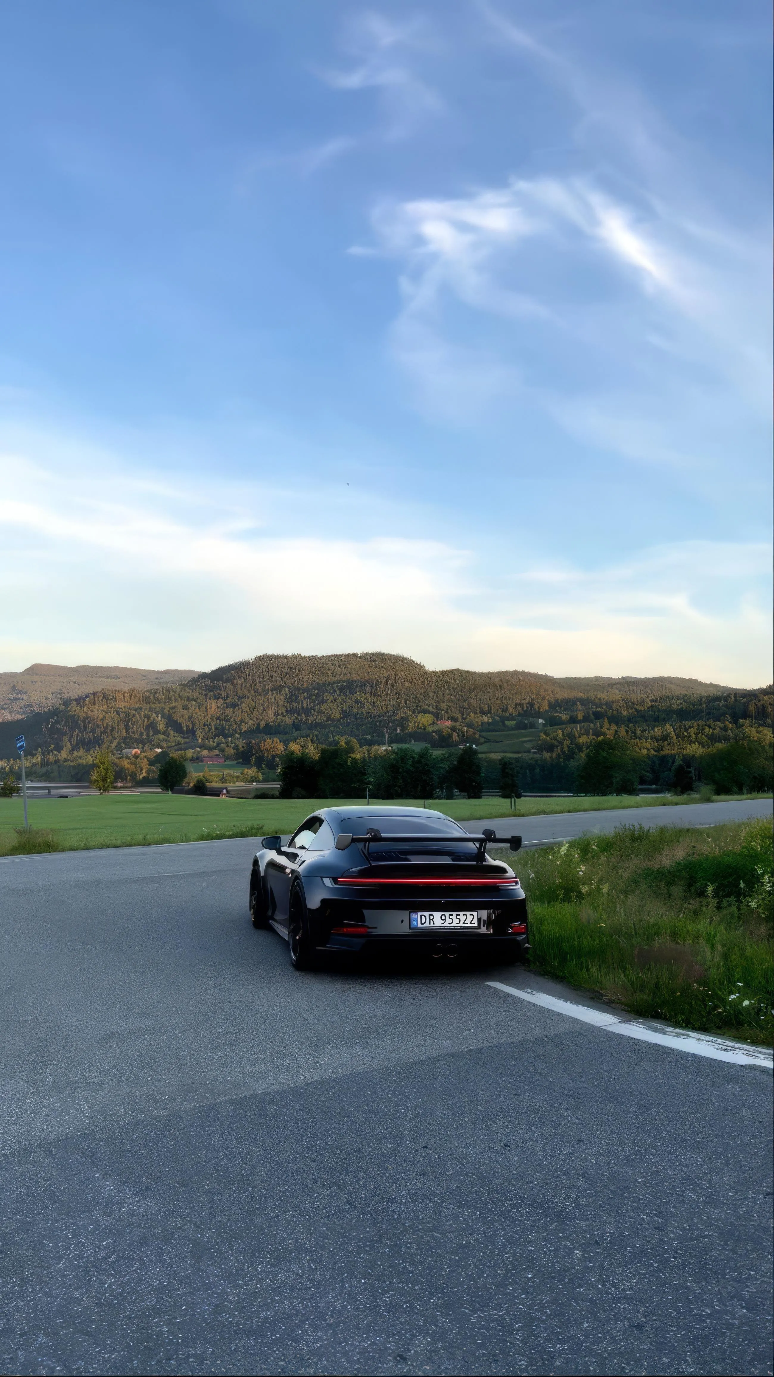 Sports Car on Open Road Under Blue Sky and Clouds Image