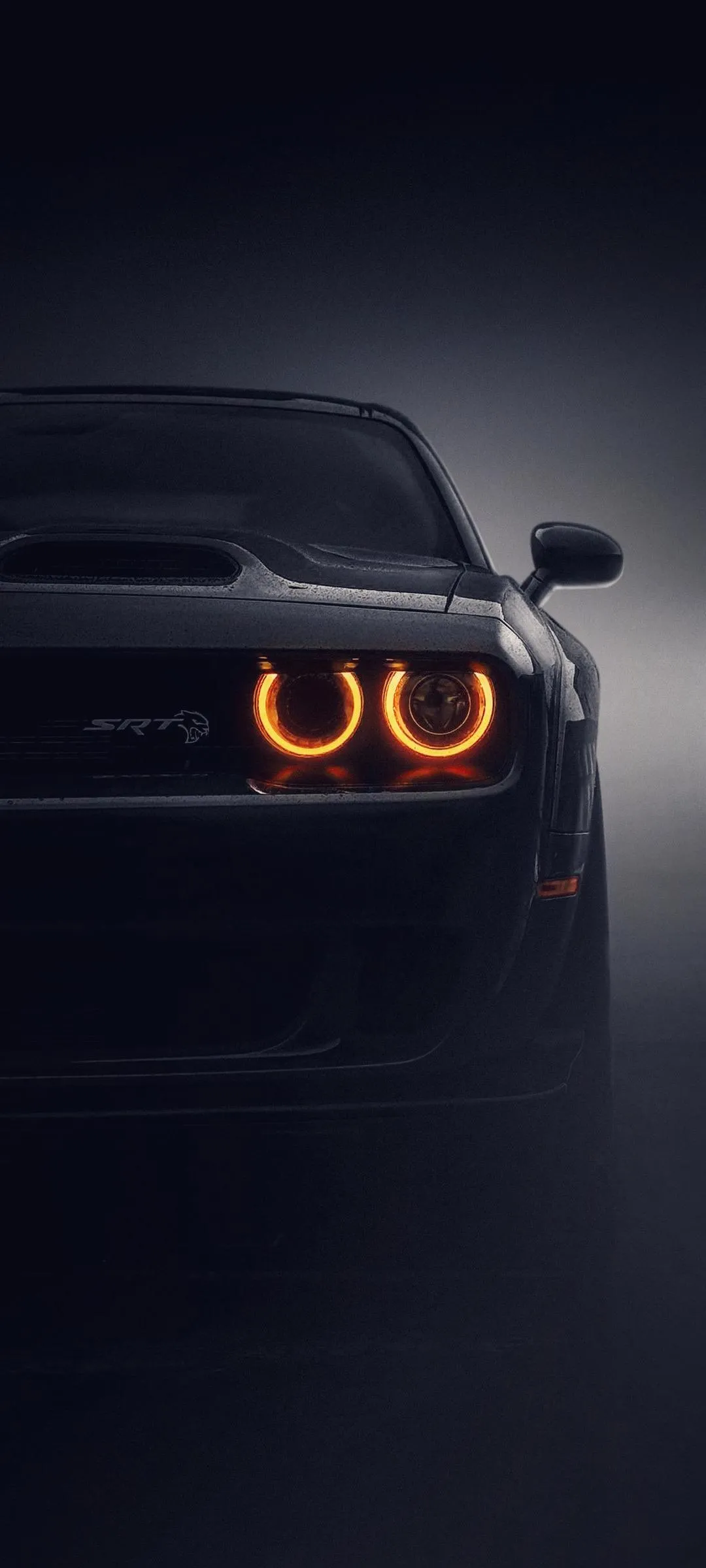 Sports Car with Orange Eyes Under Dark Streetlight Wallpaper