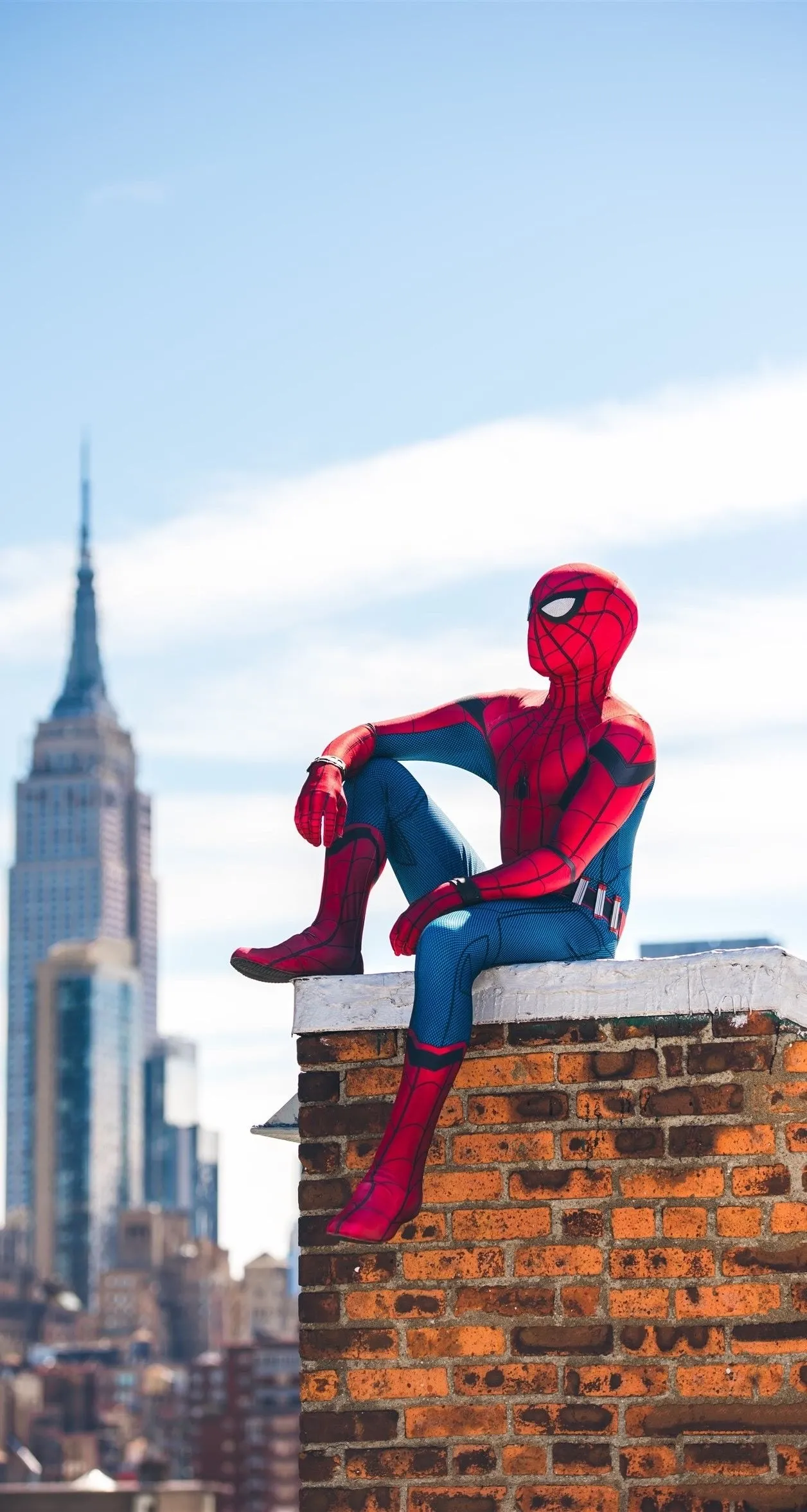 Superhero in Red Suit Sitting on Urban Ledge Wallpaper