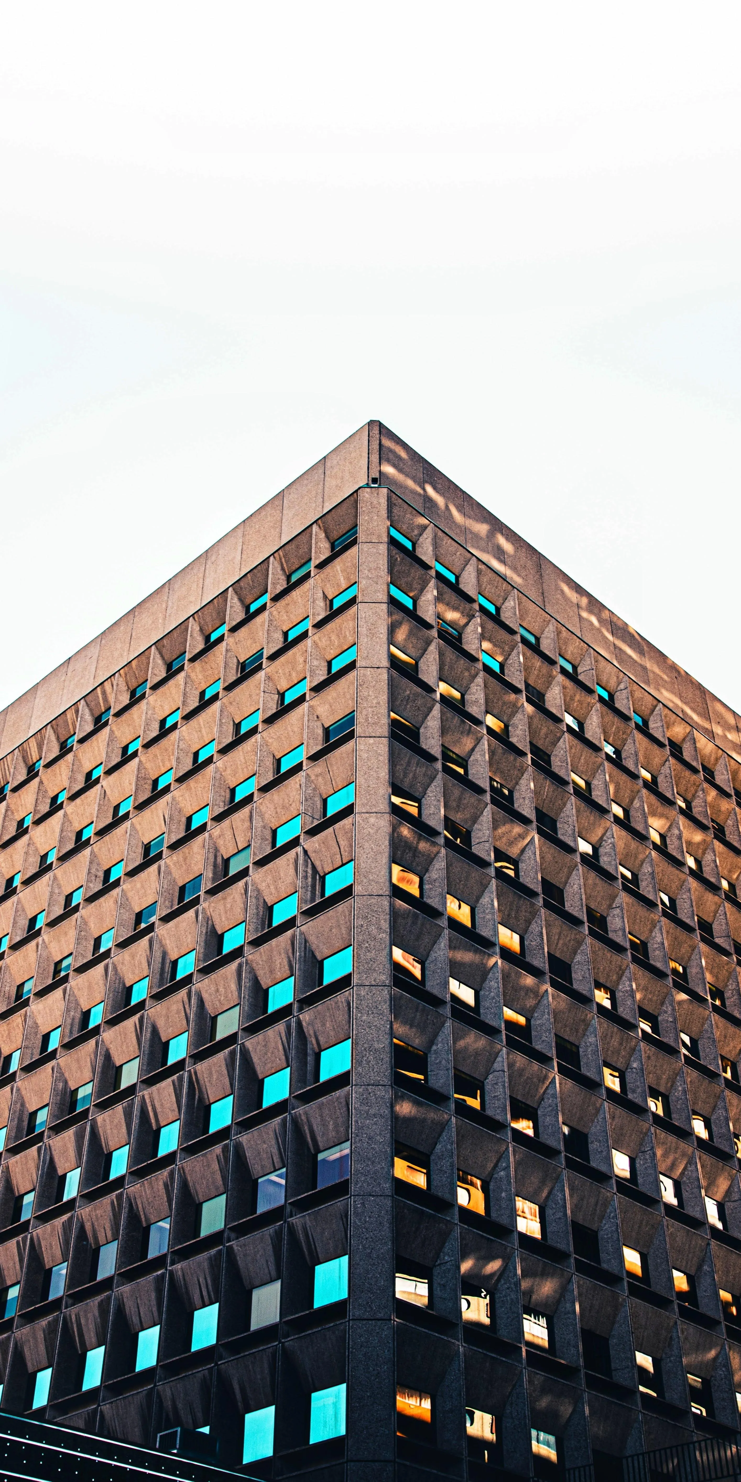 Tall Building with Reflective Windows Under White Sky
