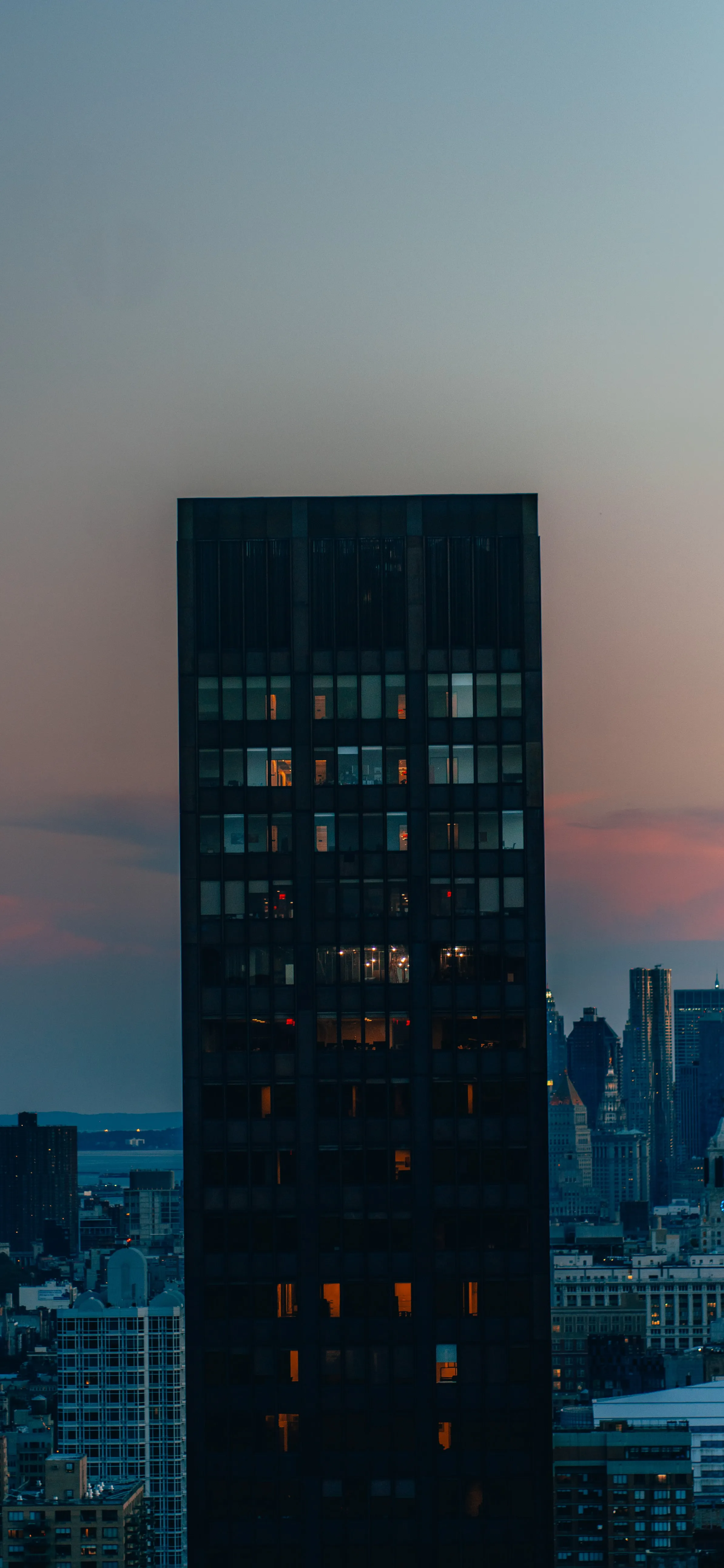 Tall Skyscraper Building at Dusk with City Skyline Behind