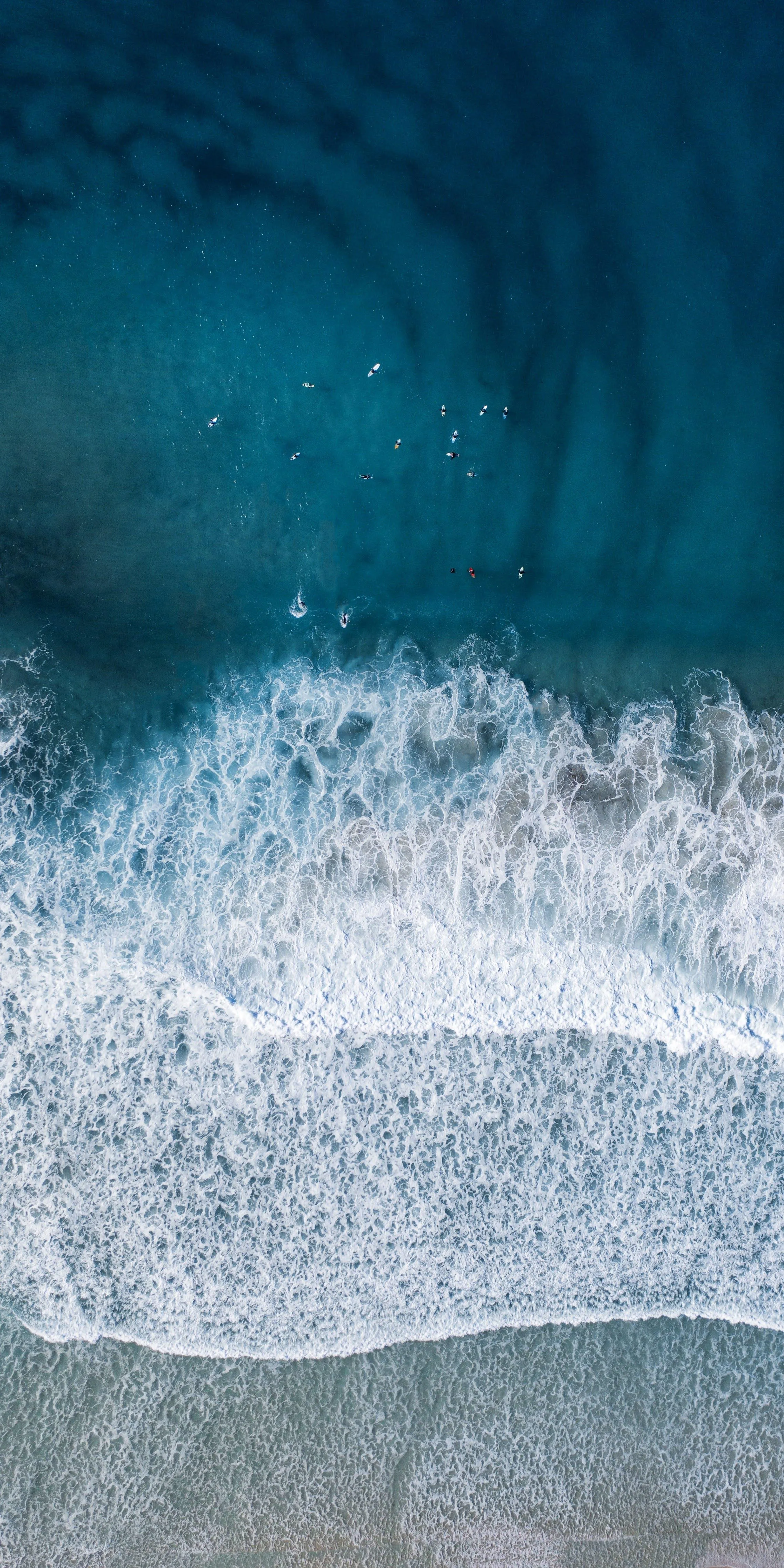 Top View of Ocean Waves Crashing on Sandy Shoreline
