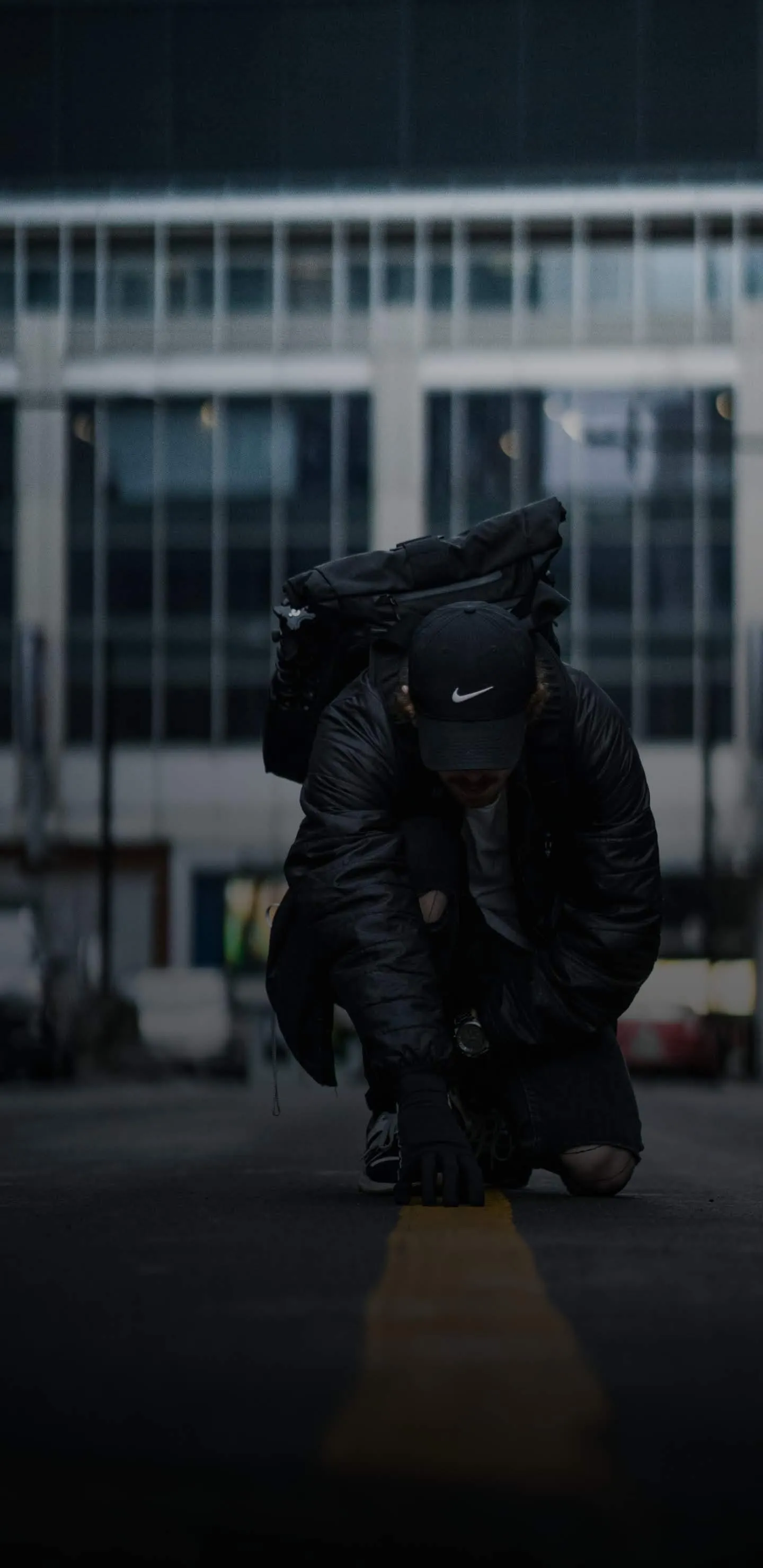 Urban Explorer Kneeling on City Street with Backpack
