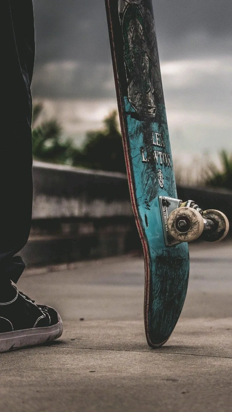 Urban Skateboard Close Up on Wet Street Surface Wallpaper