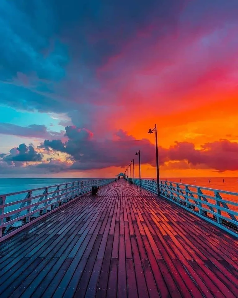 Vibrant Sunset Sky Over Pier with Warm Tones Wallpaper