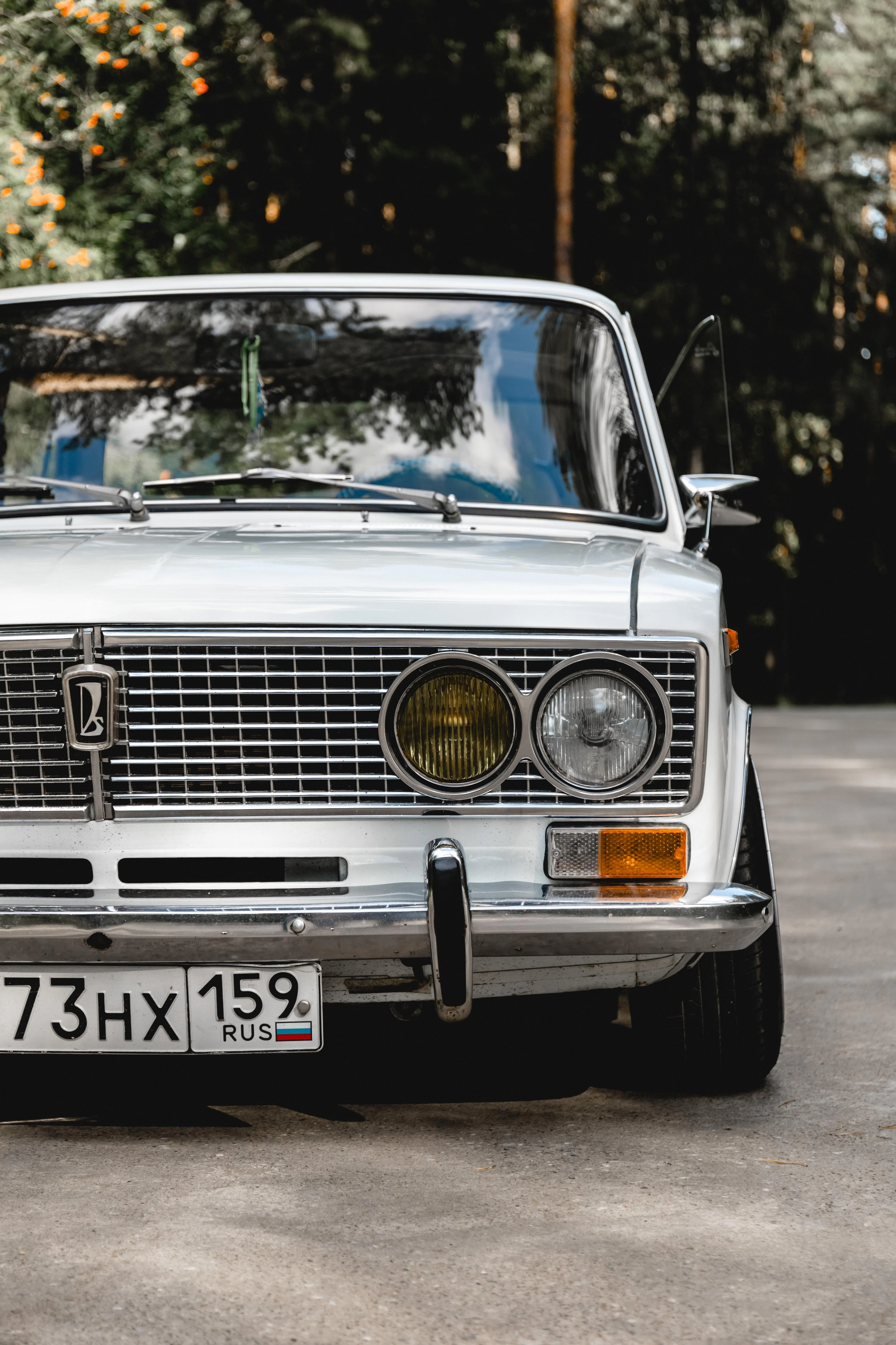 Vintage White Car Parked Near Trees and Nature Scene