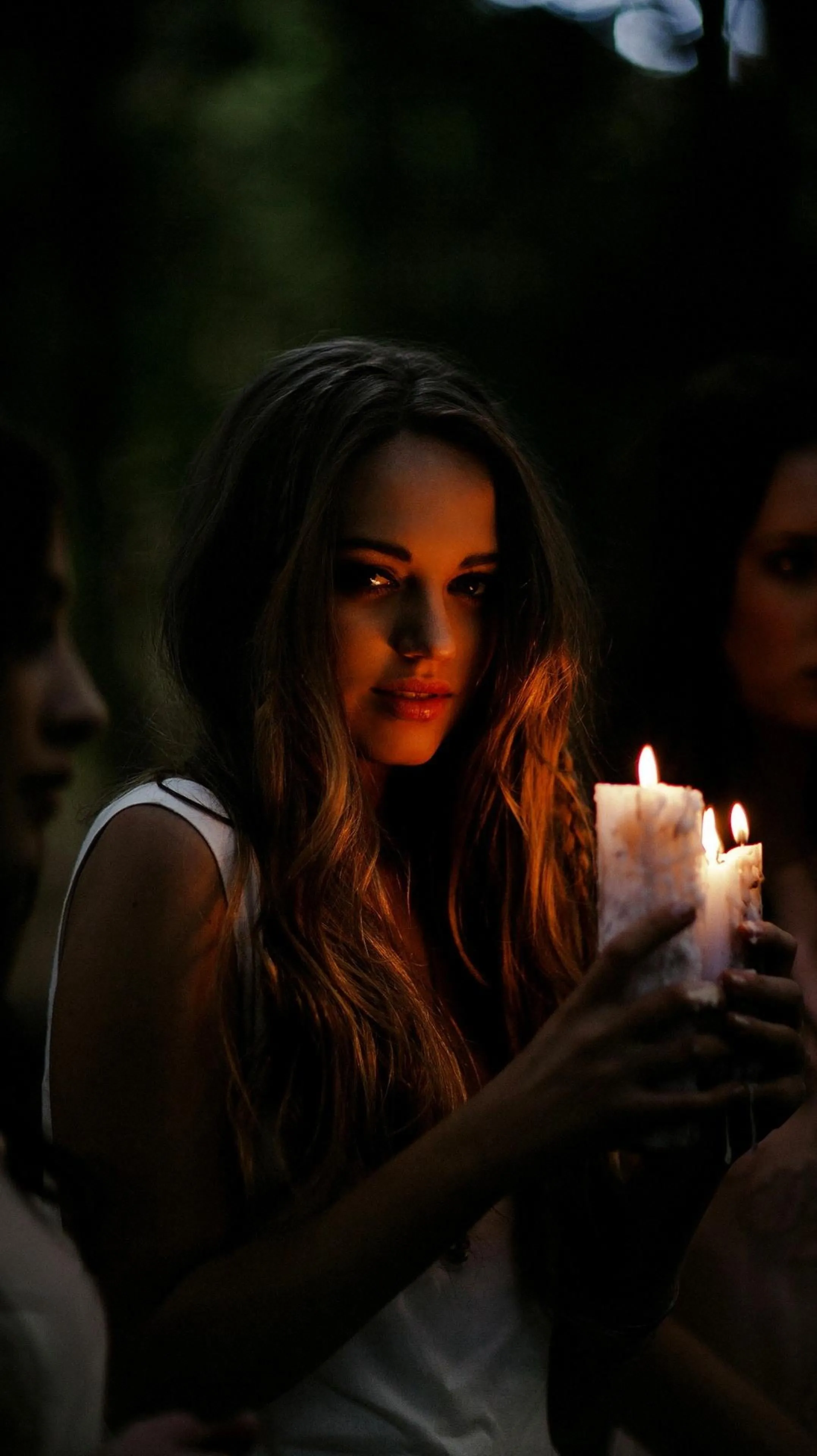 Woman Lighting Candle in a Dimly Lit Cozy Setting Wallpaper