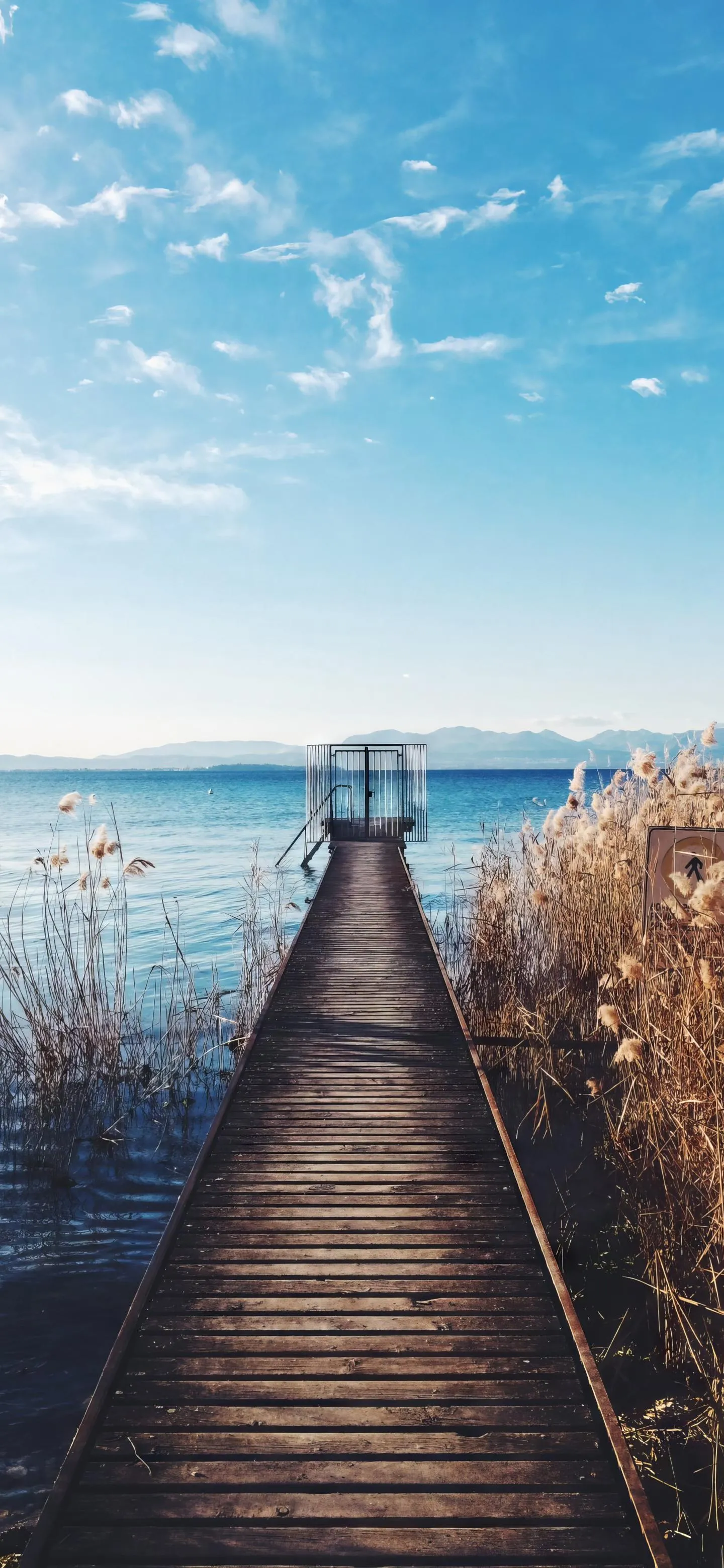 Wooden Pier Leading Out To Calm Blue Ocean and Clear Sky