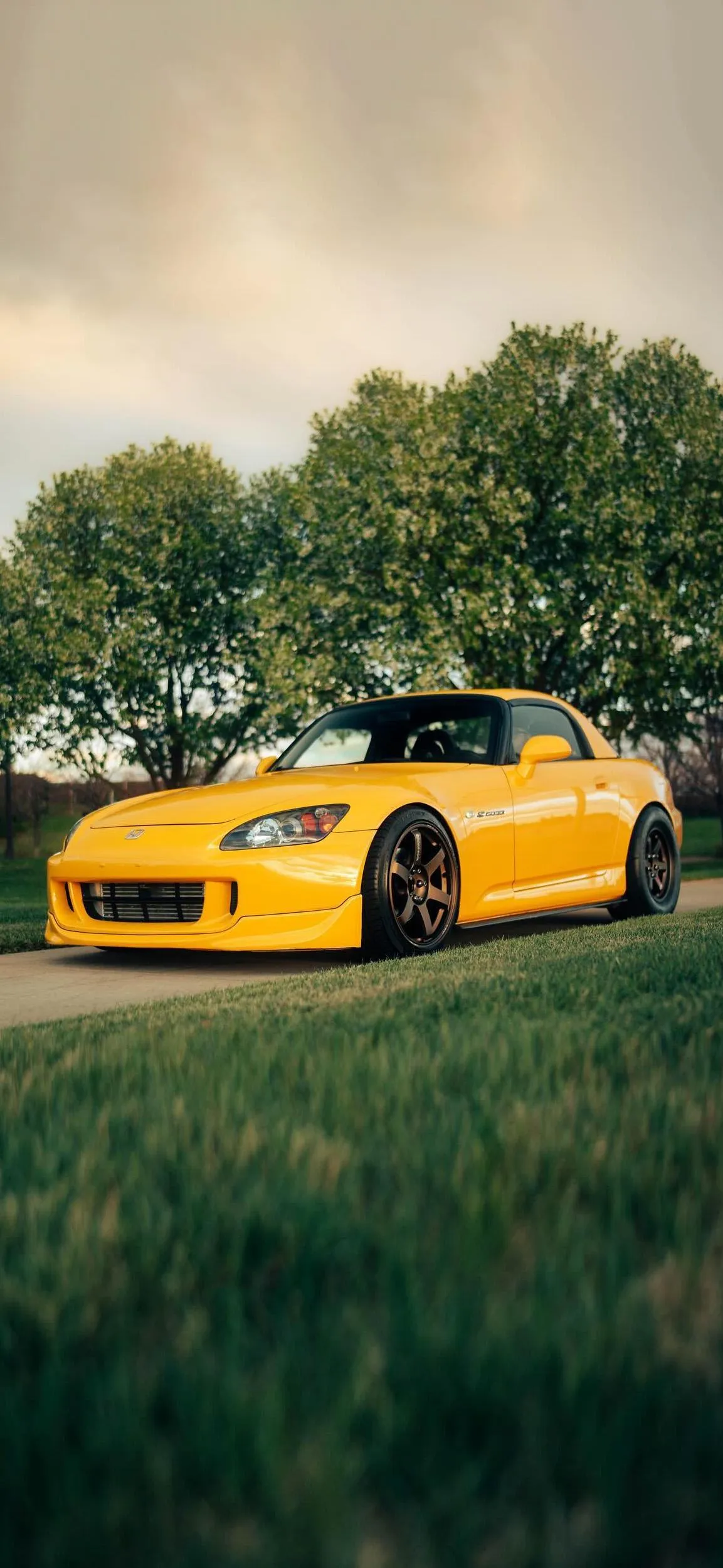 Yellow Sports Car Parked Near Lush Green Fields Wallpaper