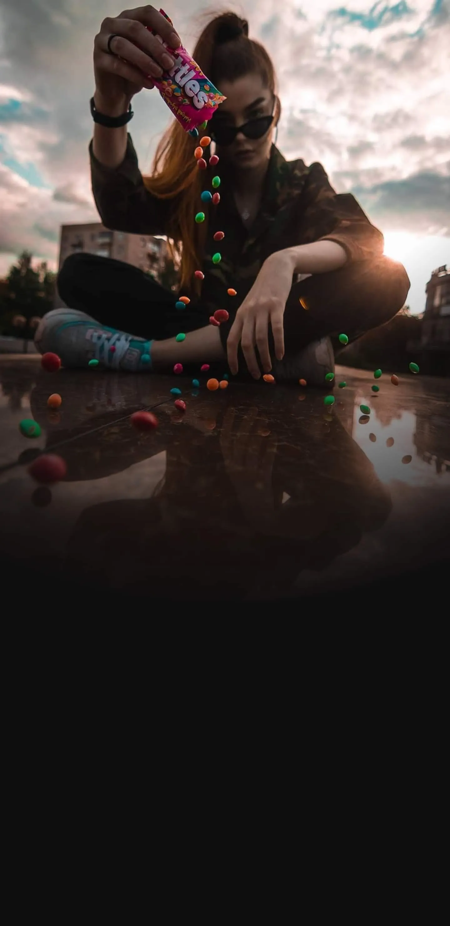 Young woman pouring colorful candies outdoors Wallpaper