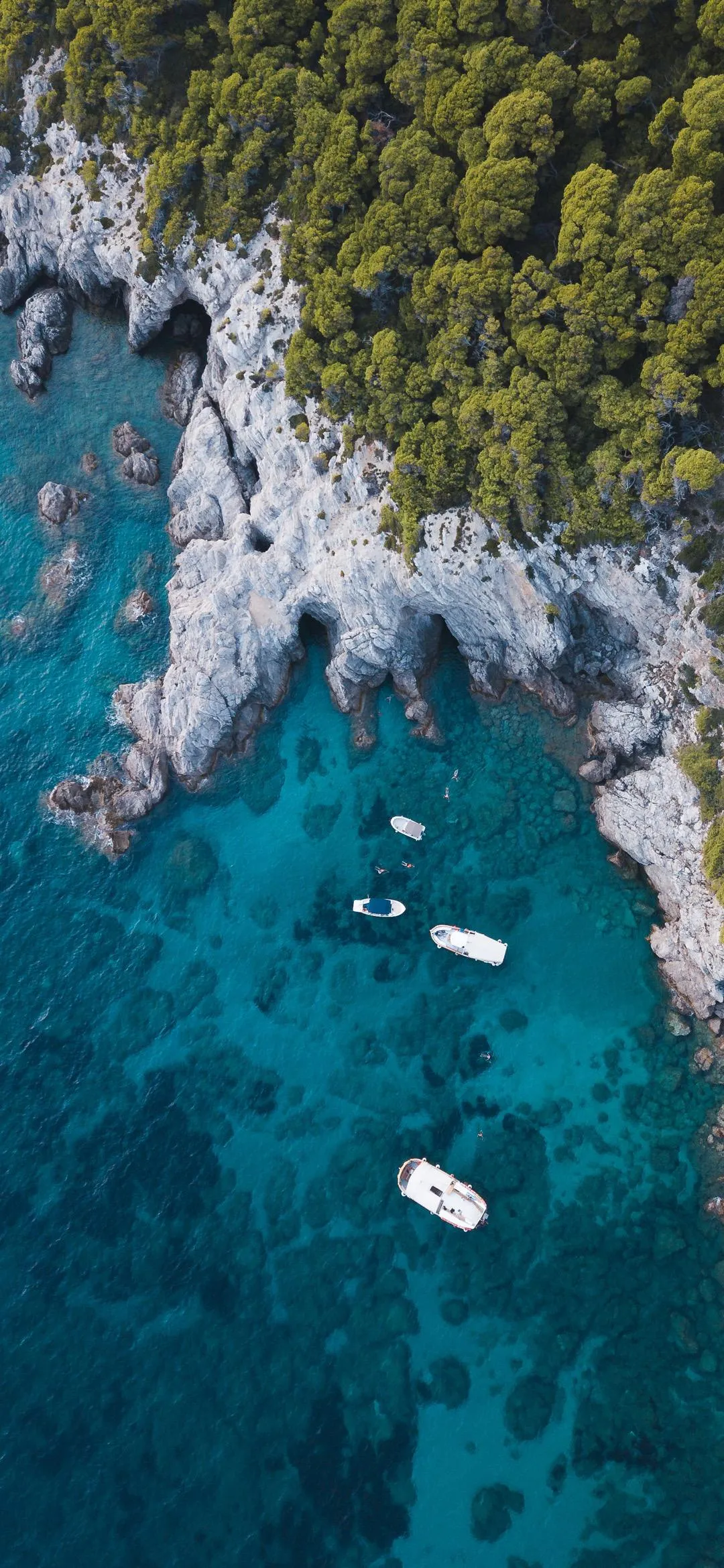 Aerial View of Boats Floating Near Rocky Shore Wallpaper