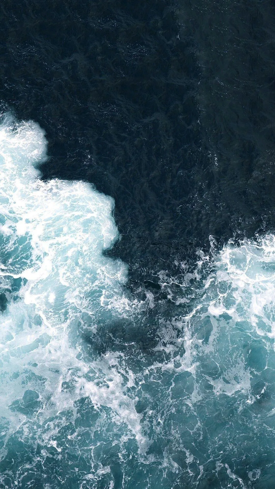 Aerial View of Ocean Waves Crashing on Rocky Coast Wallpaper